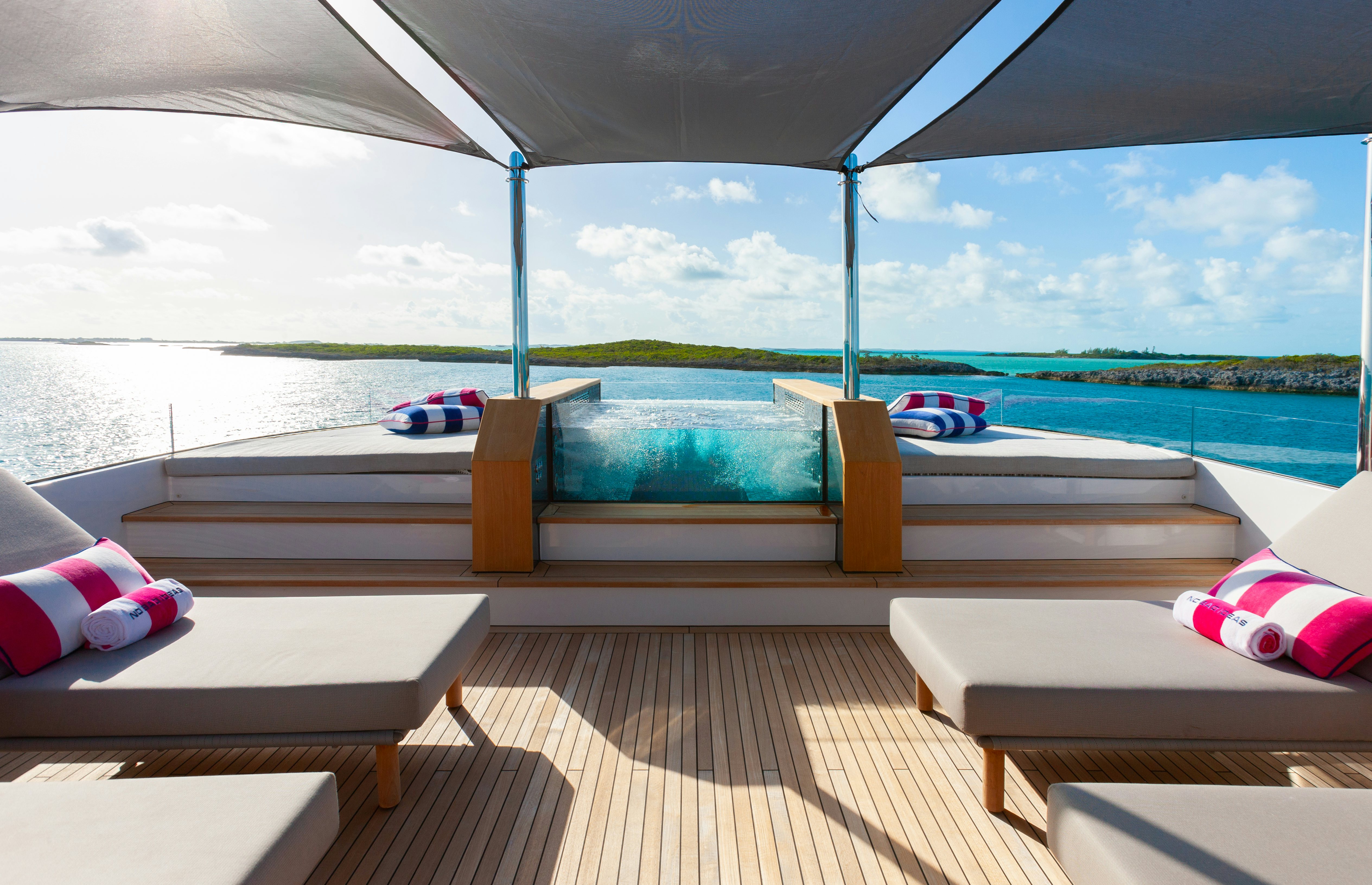 a deck with a pool and a deck overlooking a beach aboard NO BAD IDEAS Yacht for Sale