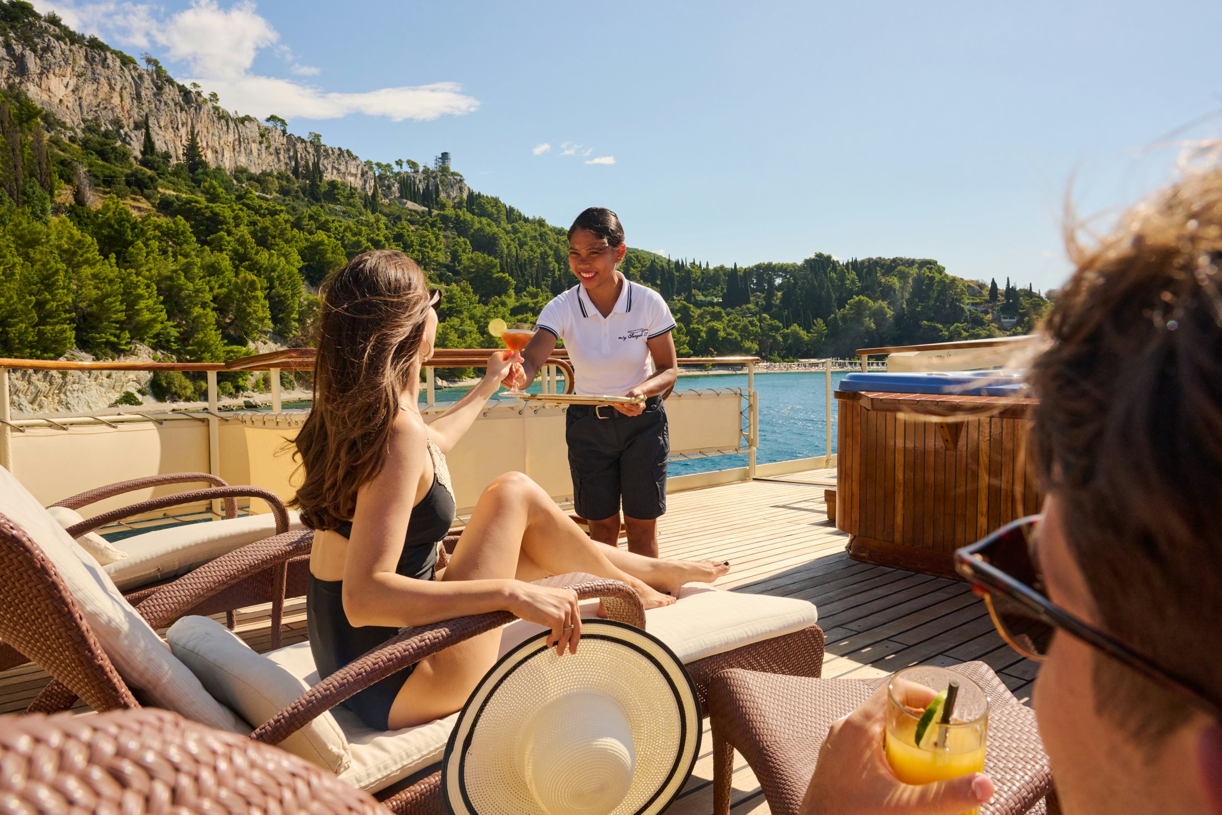 a man and woman sitting on a deck with a woman holding a drink aboard SEAGULL II Yacht for Charter
