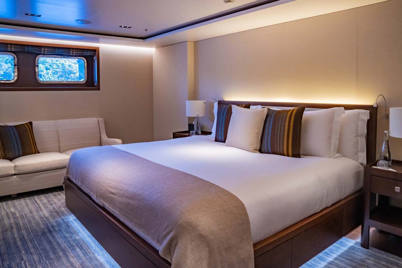 a bed with a couch and a television on the wall aboard PLANET NINE Yacht for Sale