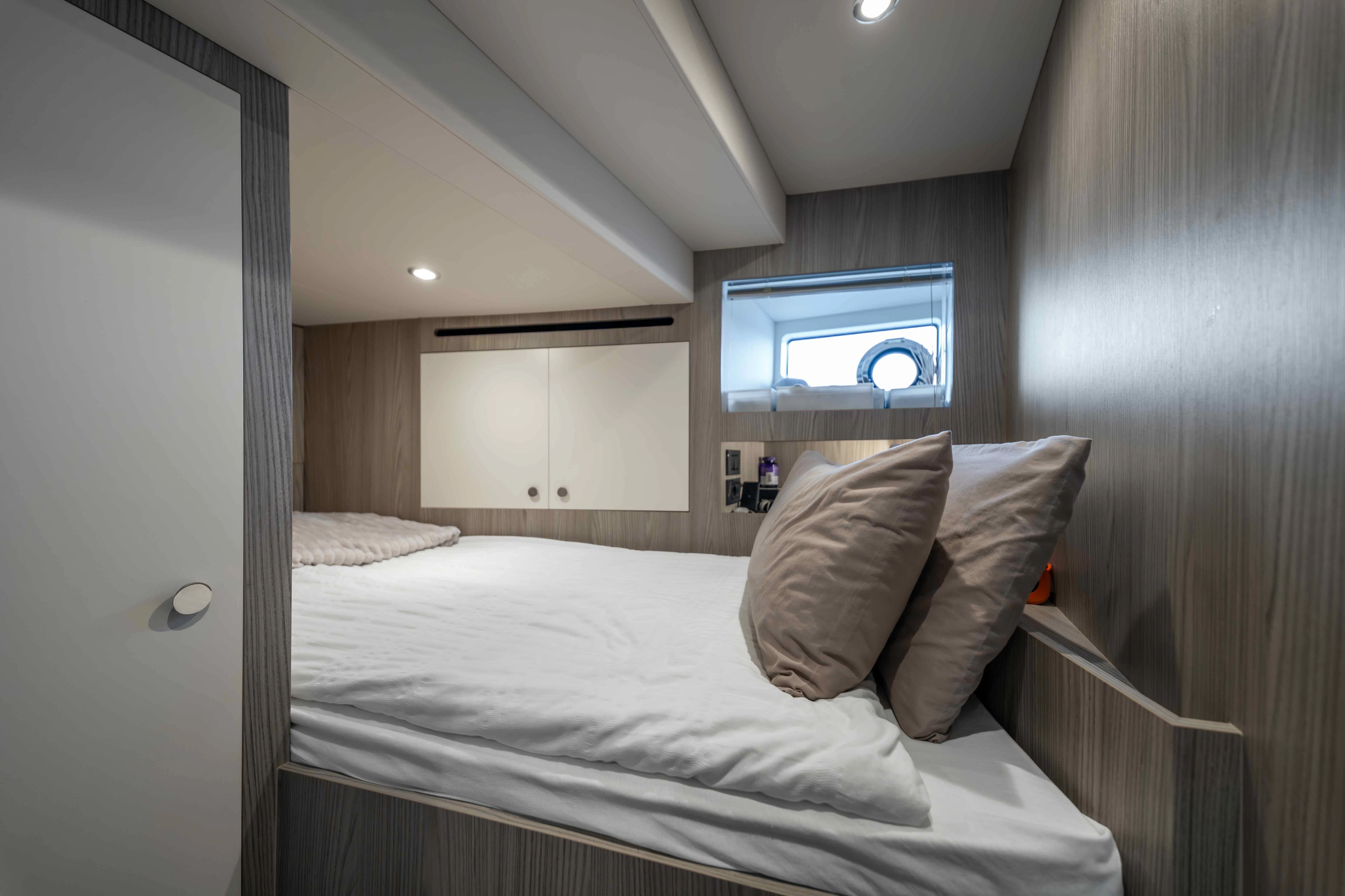 a bed with a white sheet and a television on the wall aboard ST JUDE Yacht for Sale