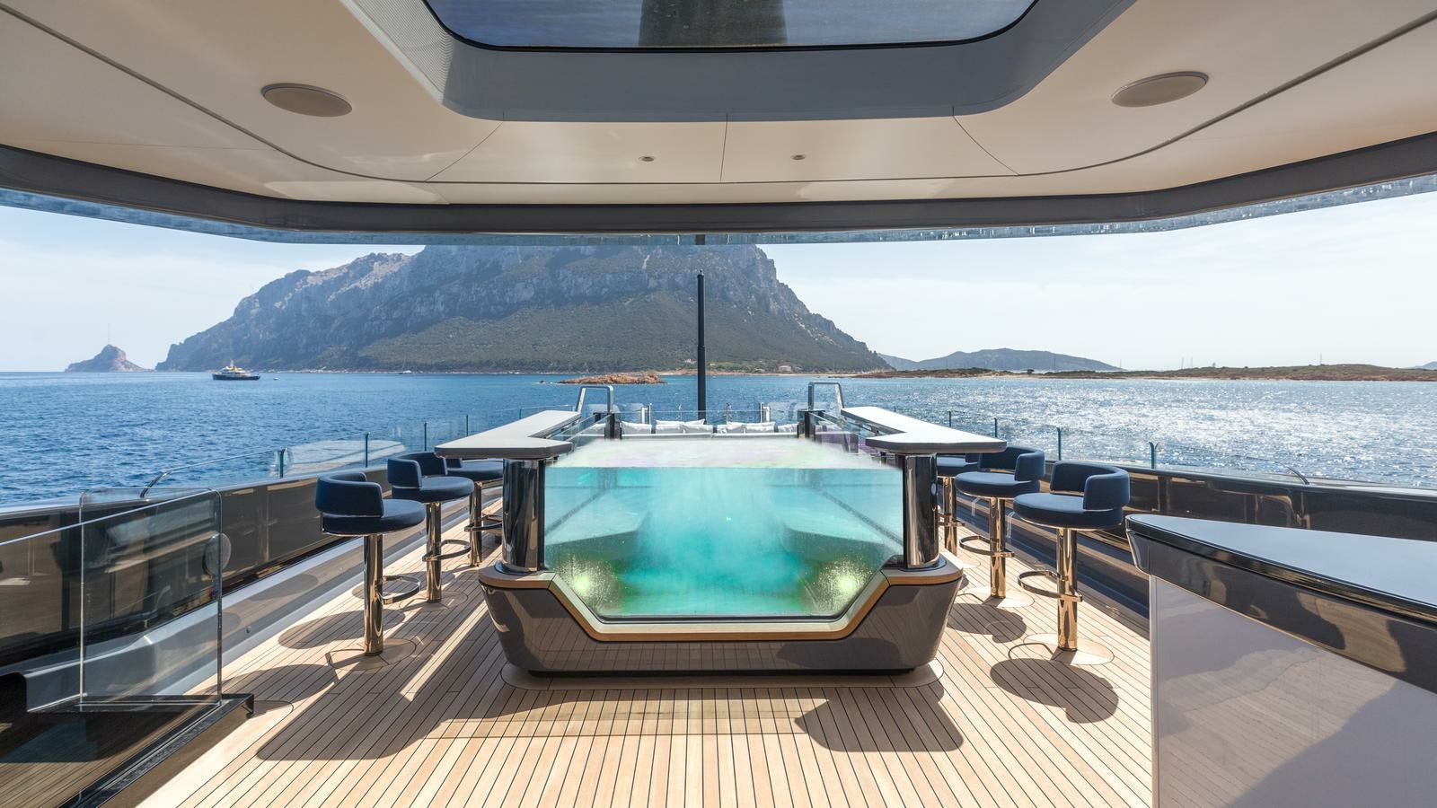 a large pool on a deck overlooking a large body of water aboard AKULA Yacht for Charter