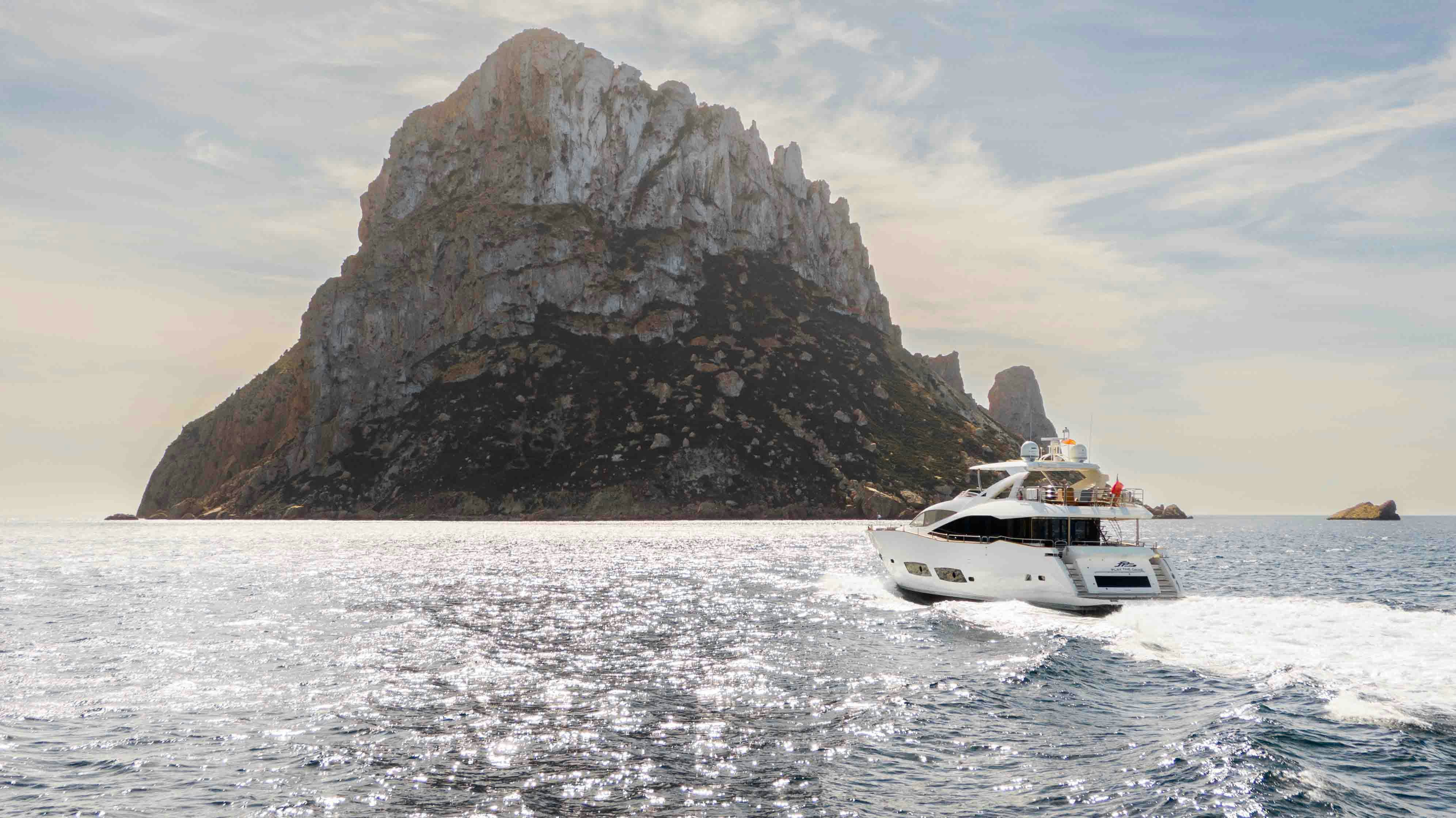 a boat sailing on the sea with Haystack Rock in the background aboard PLAY THE GAME Yacht for Sale