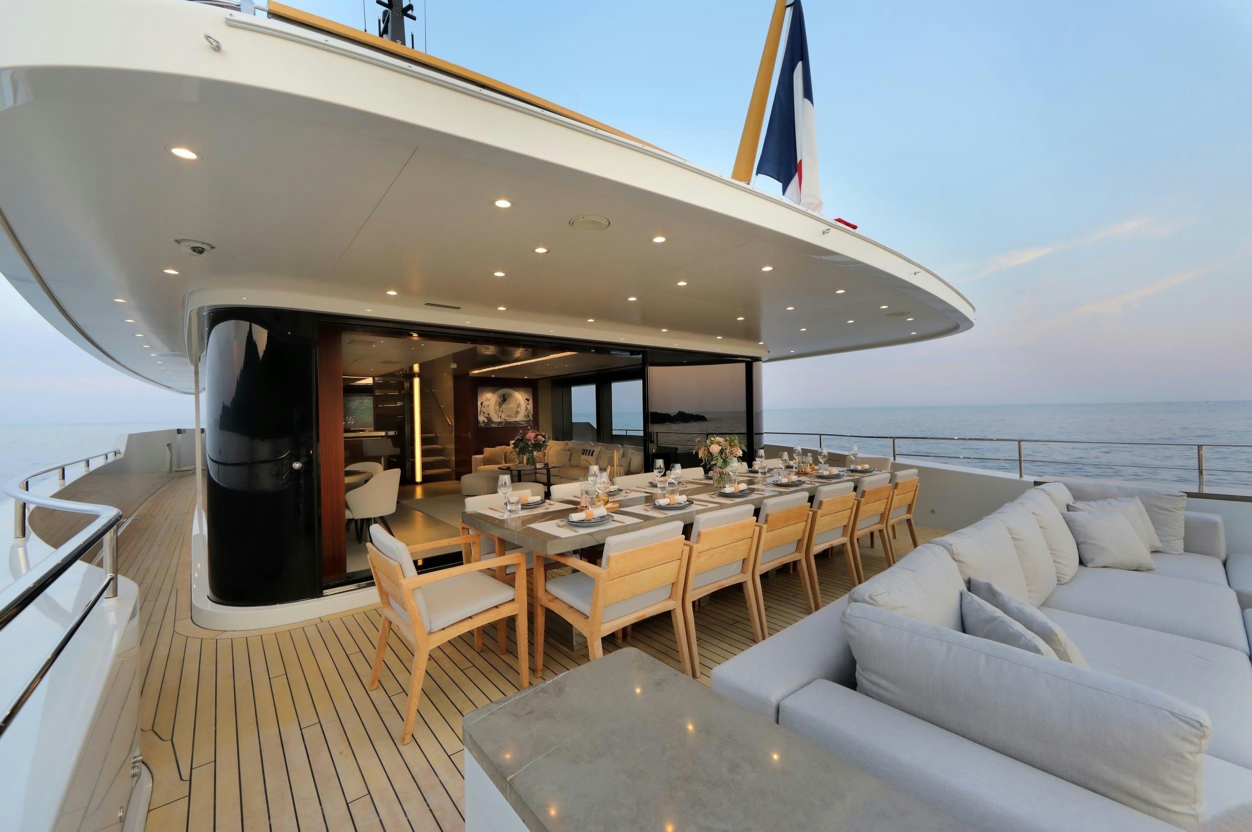 a large living room with a large table and chairs aboard X Yacht for Sale