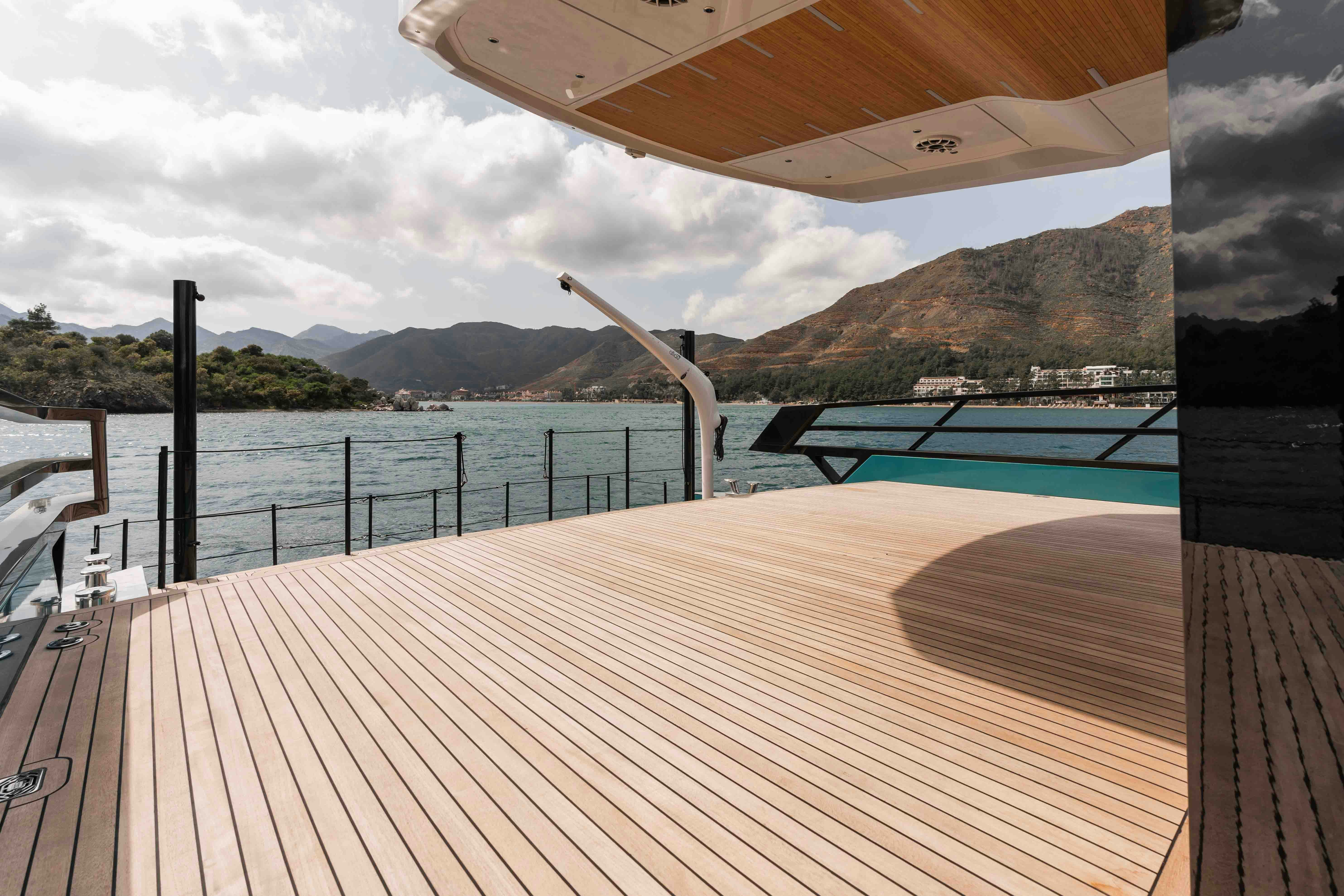 a deck with a railing and water and mountains in the background aboard NB 202 Yacht for Sale