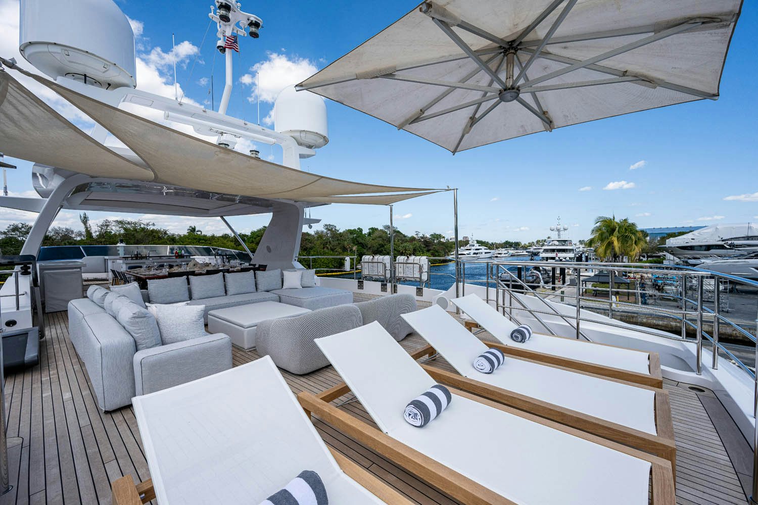 a deck with a lounge chair and a large umbrella on a sunny day aboard COFINA Yacht for Charter