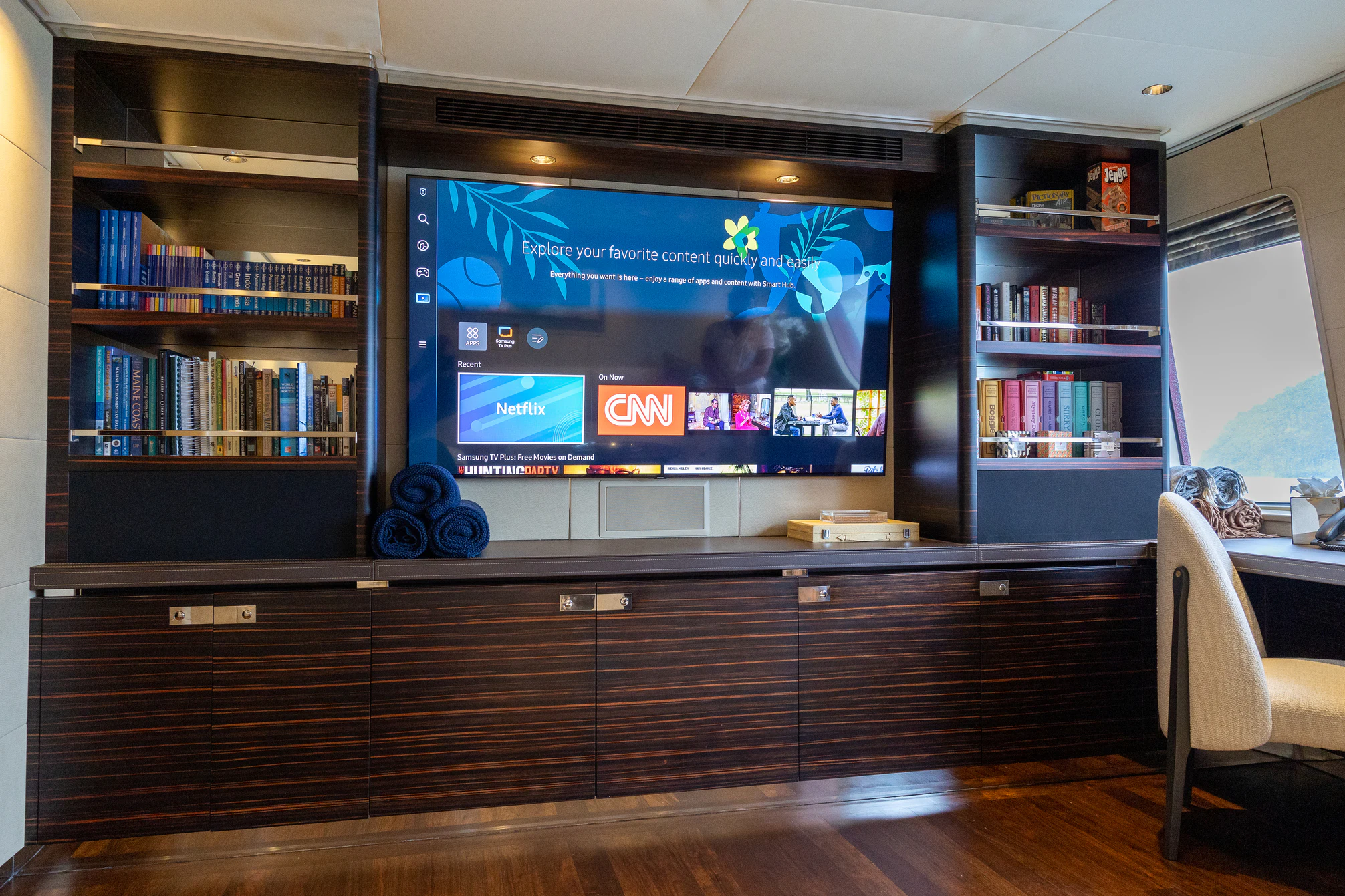 a tv on a stand in a room with a bookcase aboard AVALON Yacht for Charter