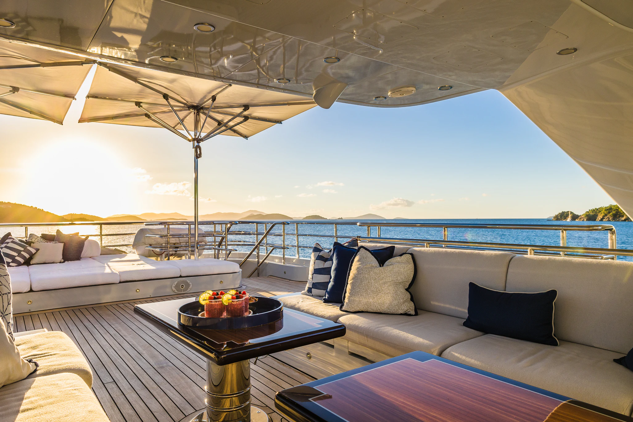 a large white lounge chair with a table and a large umbrella on a balcony with a view of aboard AVALON Yacht for Charter