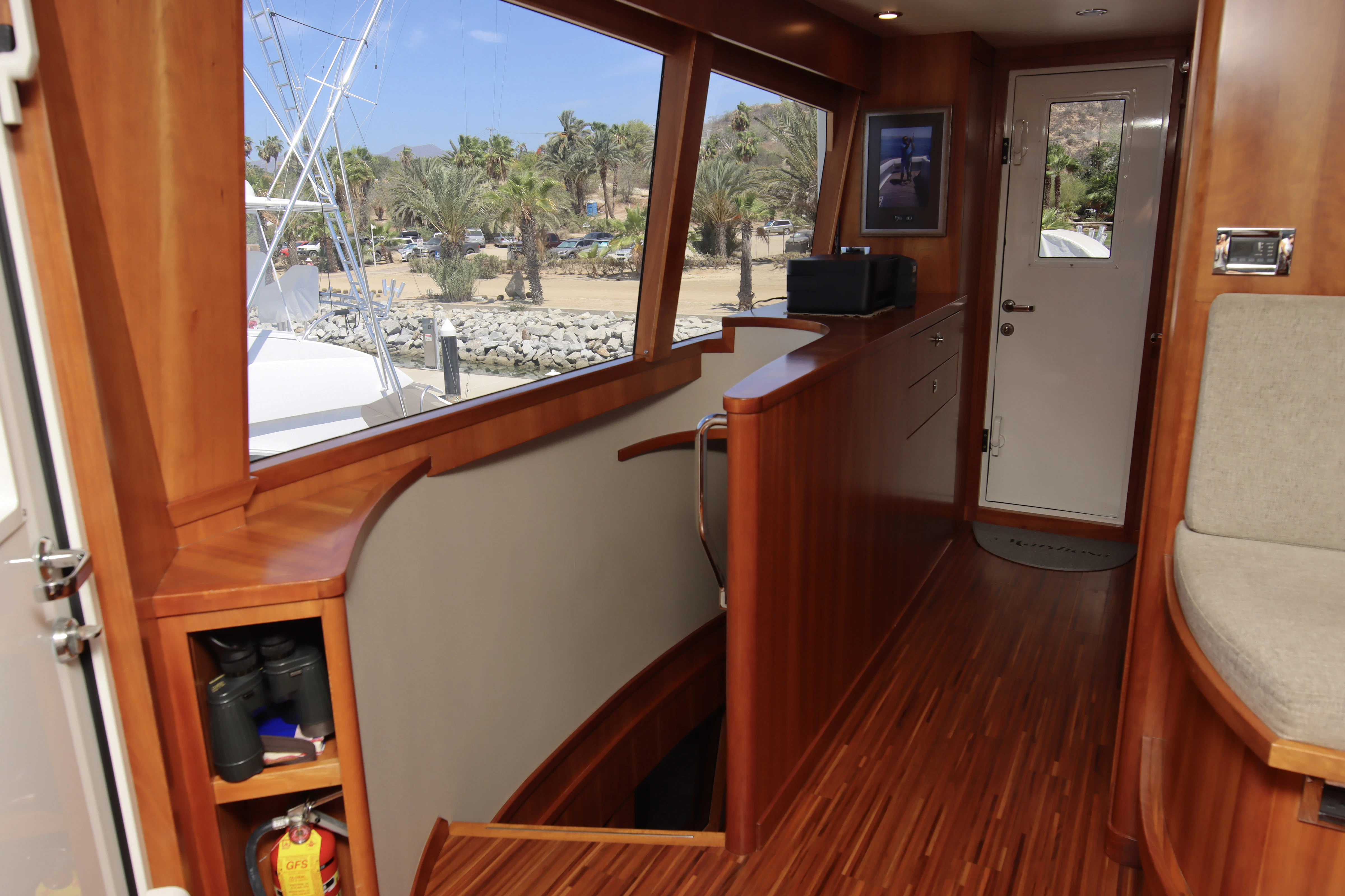 a room with a wood floor and a window with a view of the beach and trees aboard MARDIOSA Yacht for Sale