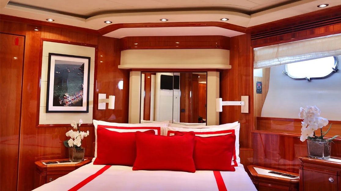 a bed with red pillows aboard CHAMPAGNE & CAVIAR Yacht for Charter