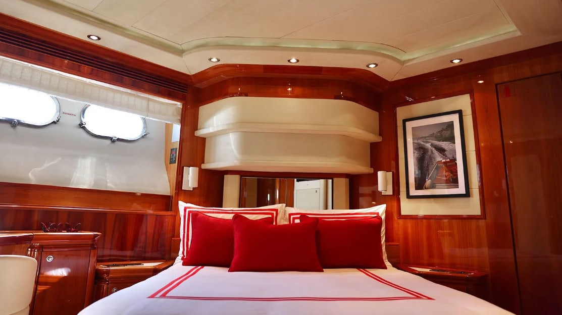 a bed with red pillows aboard CHAMPAGNE & CAVIAR Yacht for Charter