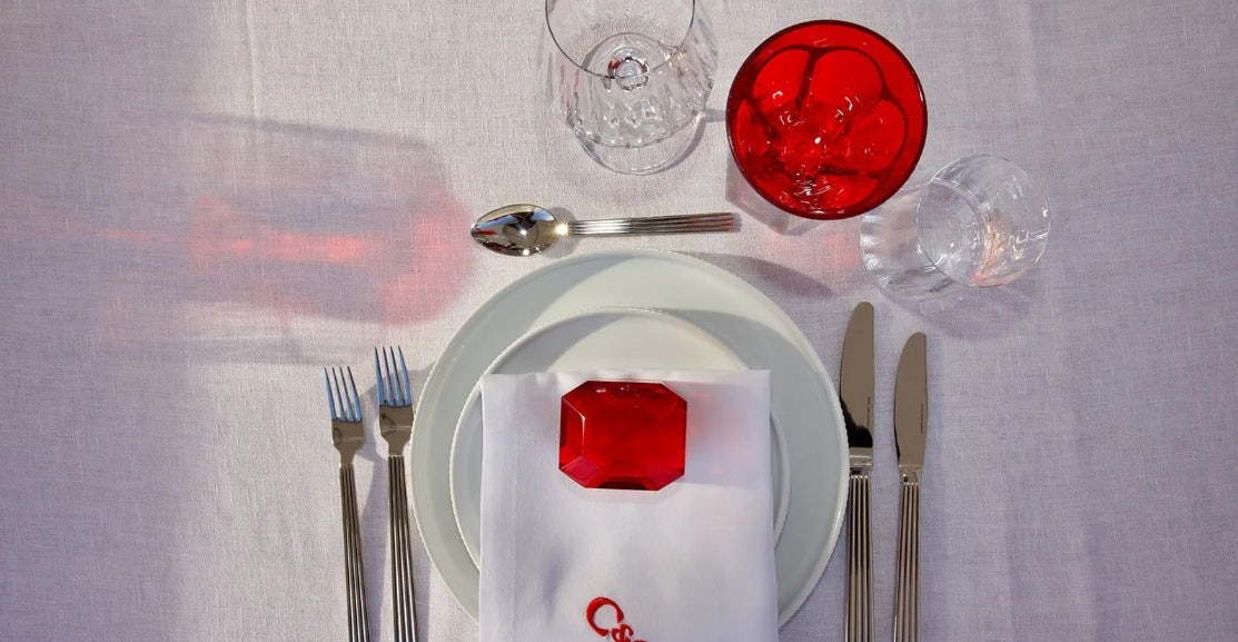 a plate with a red object on it and silverware on it aboard CHAMPAGNE & CAVIAR Yacht for Charter