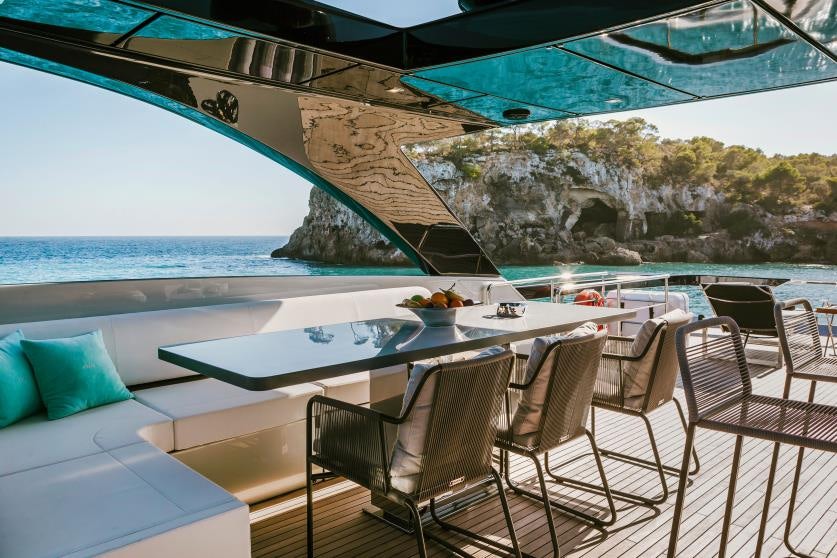 a table and chairs on a deck overlooking a body of water aboard BARRACUDA III Yacht for Charter