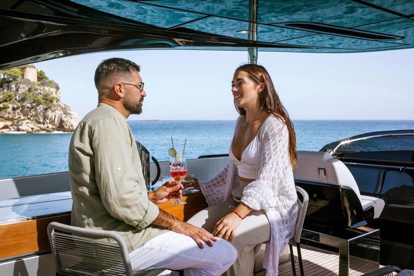 a man and woman sitting on a boat with drinks and a view of the ocean aboard BARRACUDA III Yacht for Charter