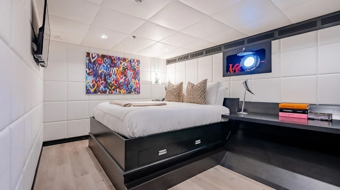 a bedroom with a bed and a tv on the wall aboard LOTUS Yacht for Charter