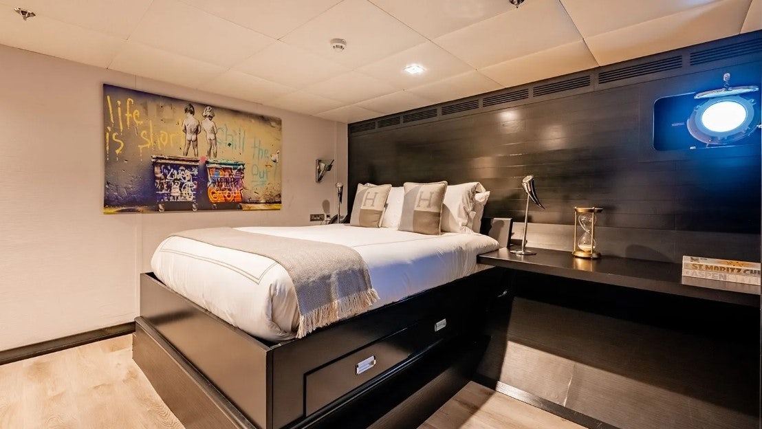 a room with a bed and a lamp on the wall aboard LOTUS Yacht for Charter