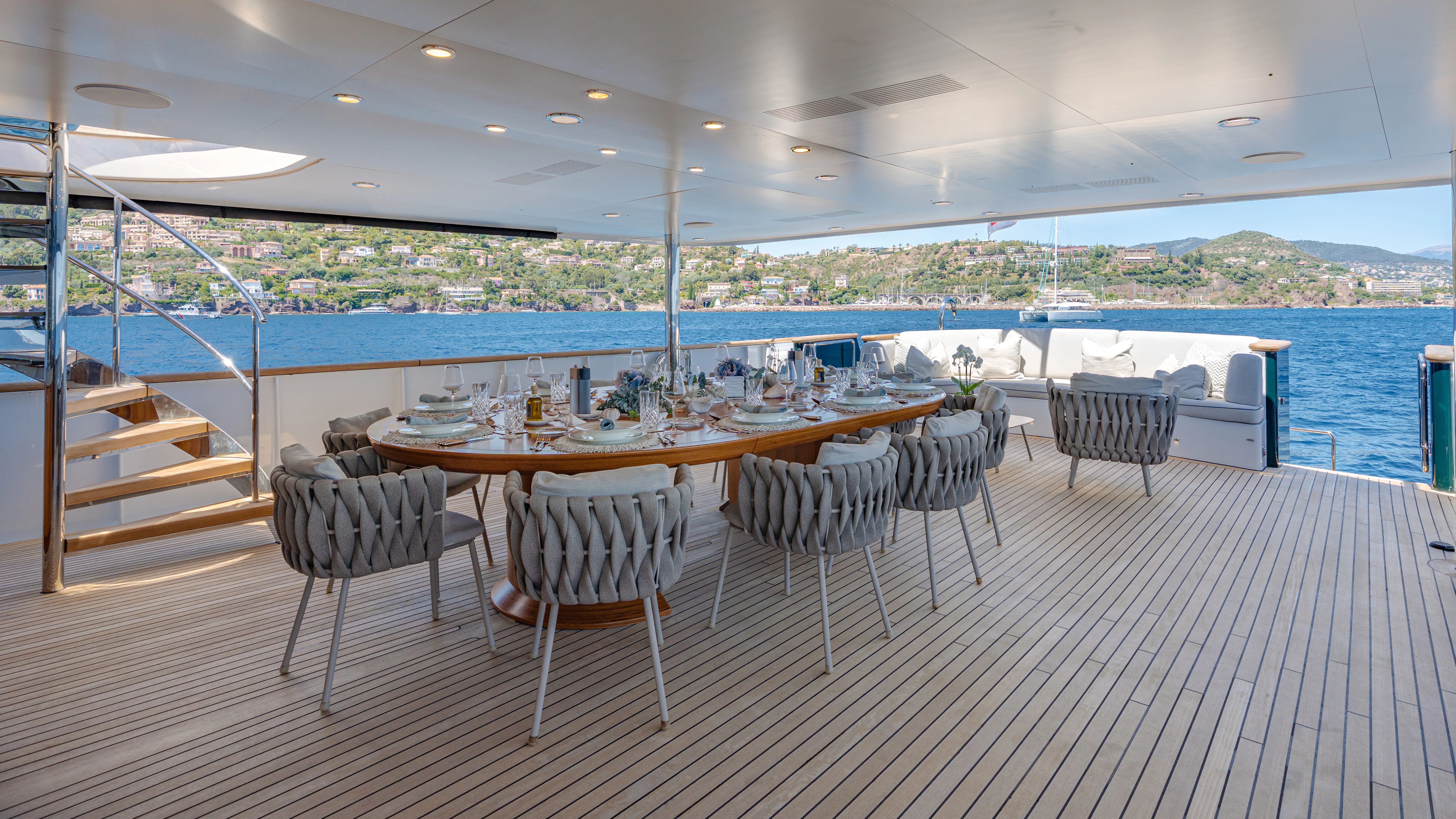 a table set for a meal on a deck overlooking a large swimming pool aboard EMERALD Yacht for Sale
