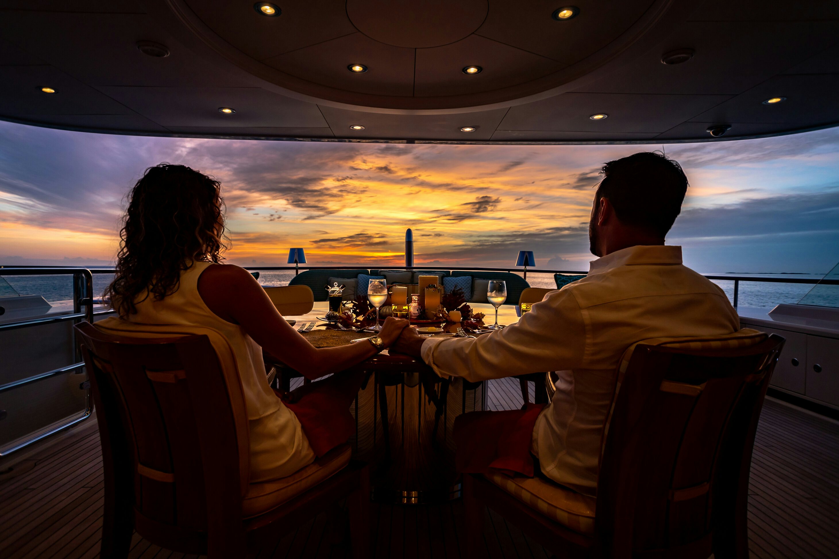 a man and woman sitting at a table looking at the water aboard SHADOWL Yacht for Charter