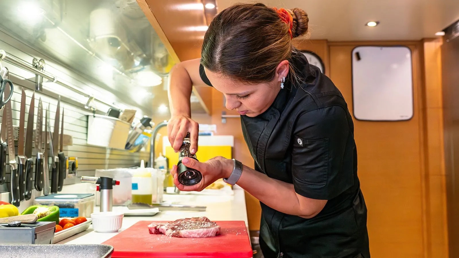 a person cutting meat in a kitchen aboard AWAY Yacht for Charter
