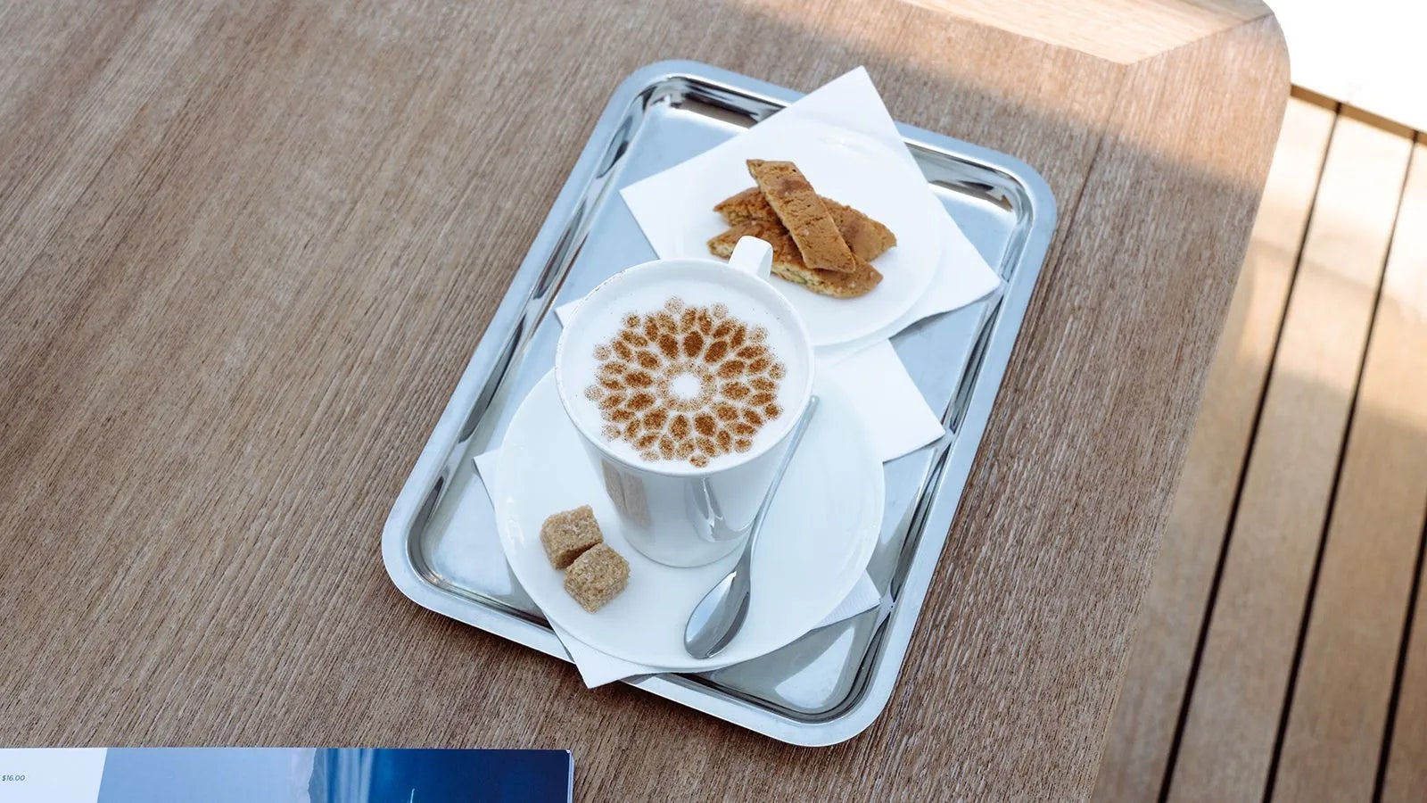 a cup of coffee and a croissant on a tray aboard AWAY Yacht for Charter