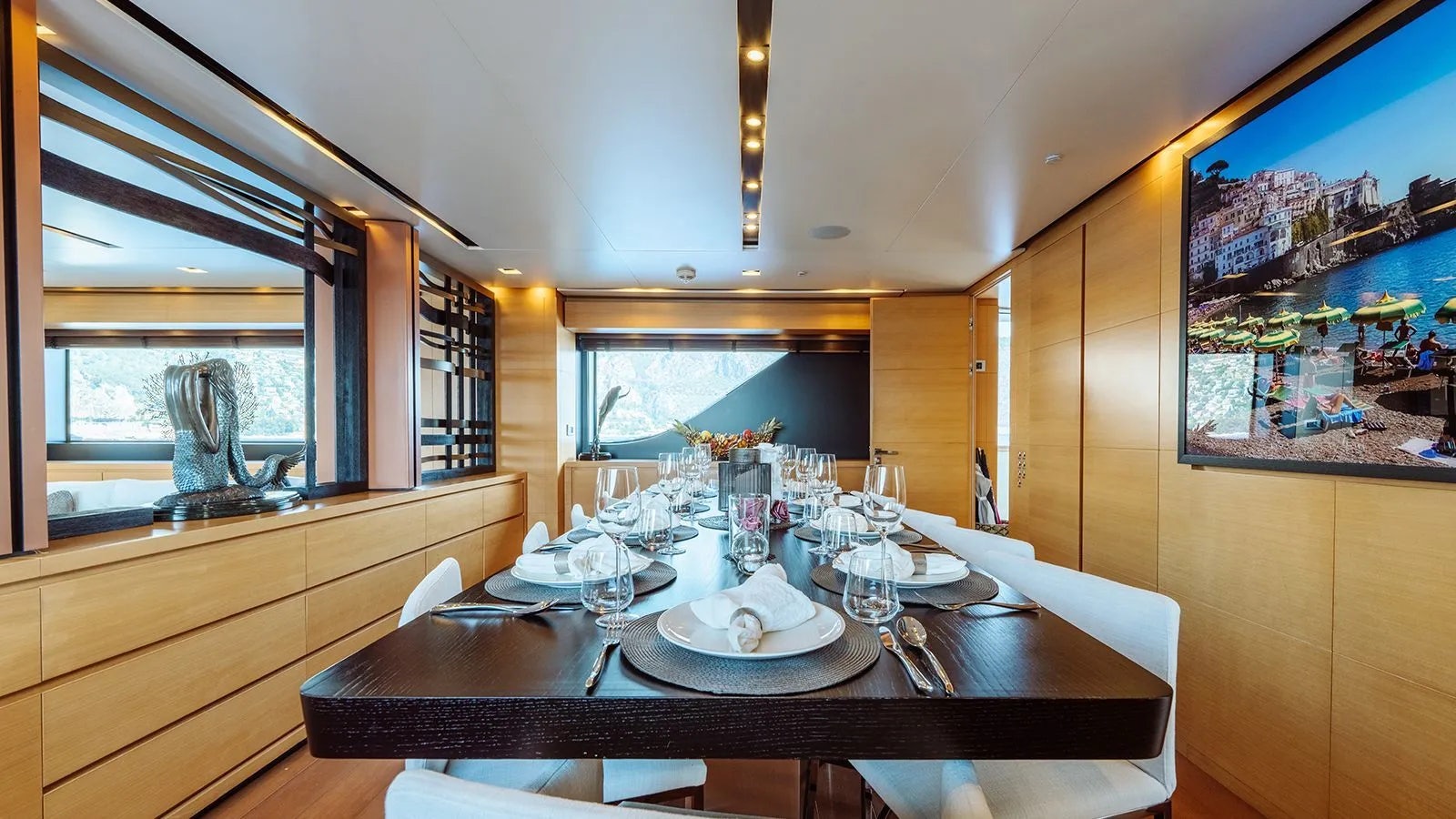a dining table with a large window aboard AWAY Yacht for Charter