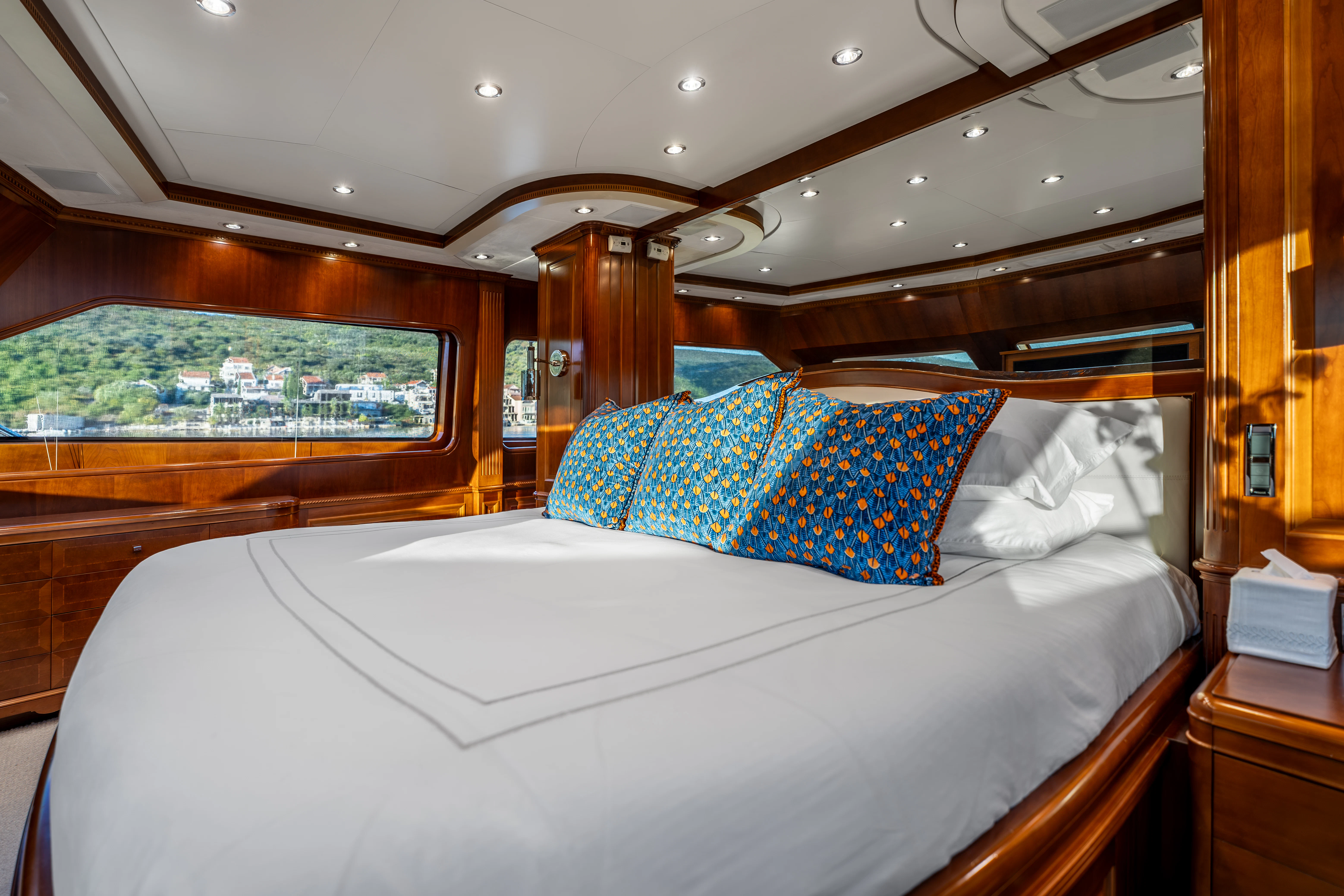 a bed with a white sheet and blue and yellow pillows aboard ARTEMIS Yacht for Sale