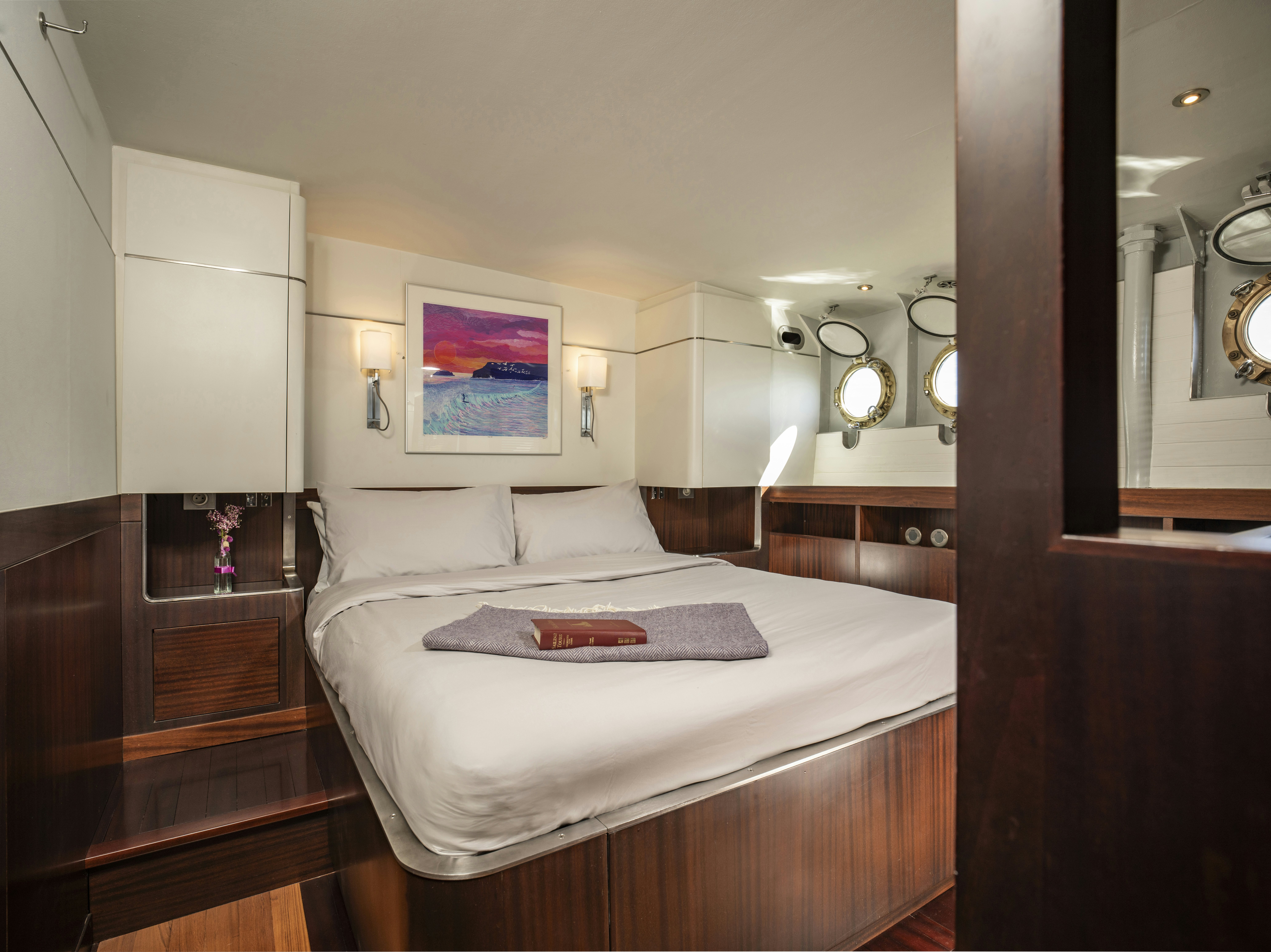 a bed with a white sheet and a mirror above it aboard LA FENICE Yacht for Sale