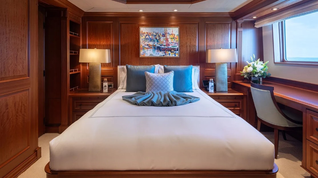 a bed with a white sheet and pillows on it aboard CROSSED SABRE Yacht for Charter