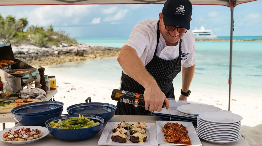a man cooking food on a table aboard CROSSED SABRE Yacht for Charter