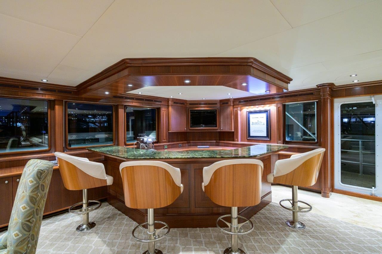 a room with a bar and chairs aboard COMPASS ROSE Yacht for Sale