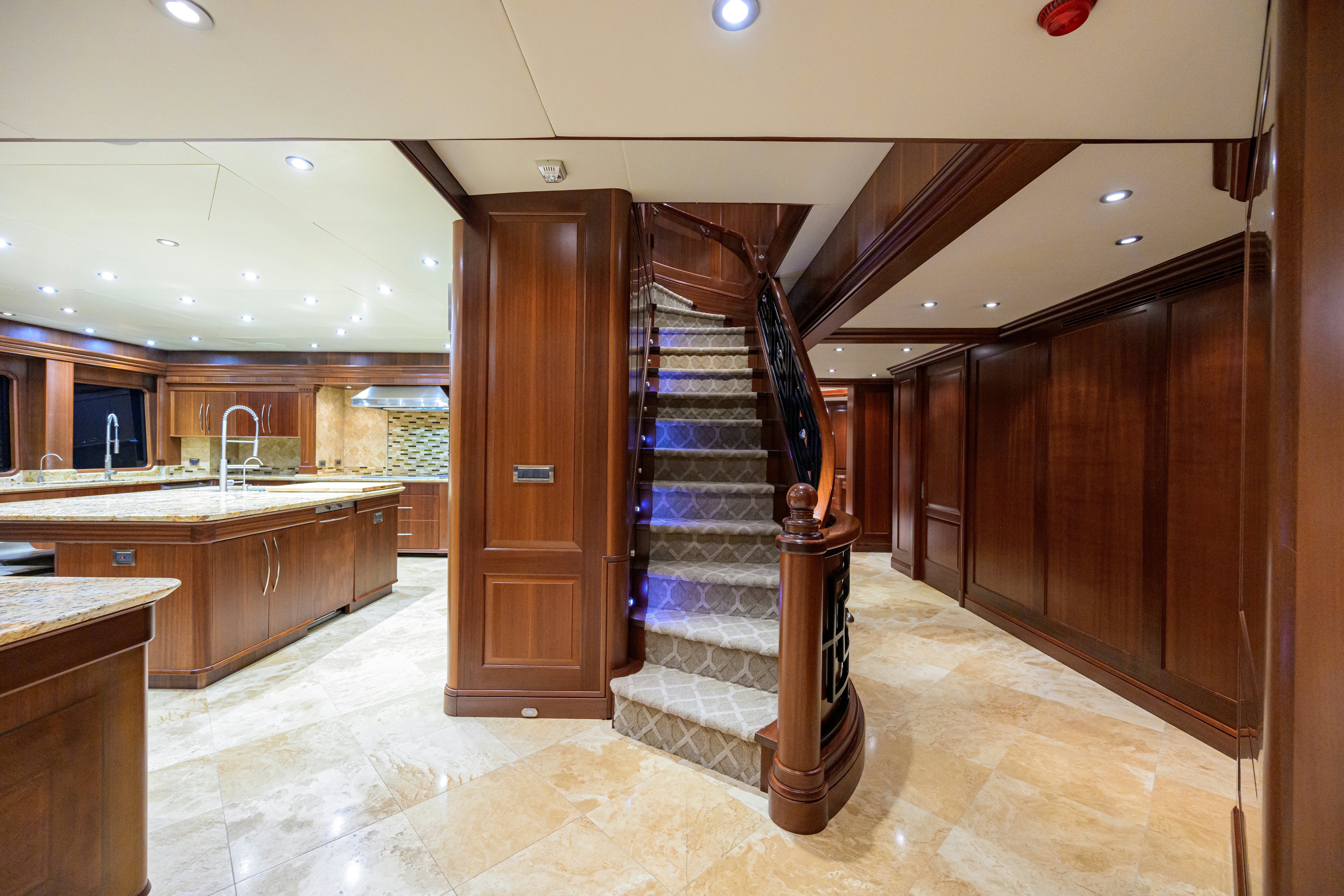 a large wooden staircase in a large room aboard COMPASS ROSE Yacht for Sale