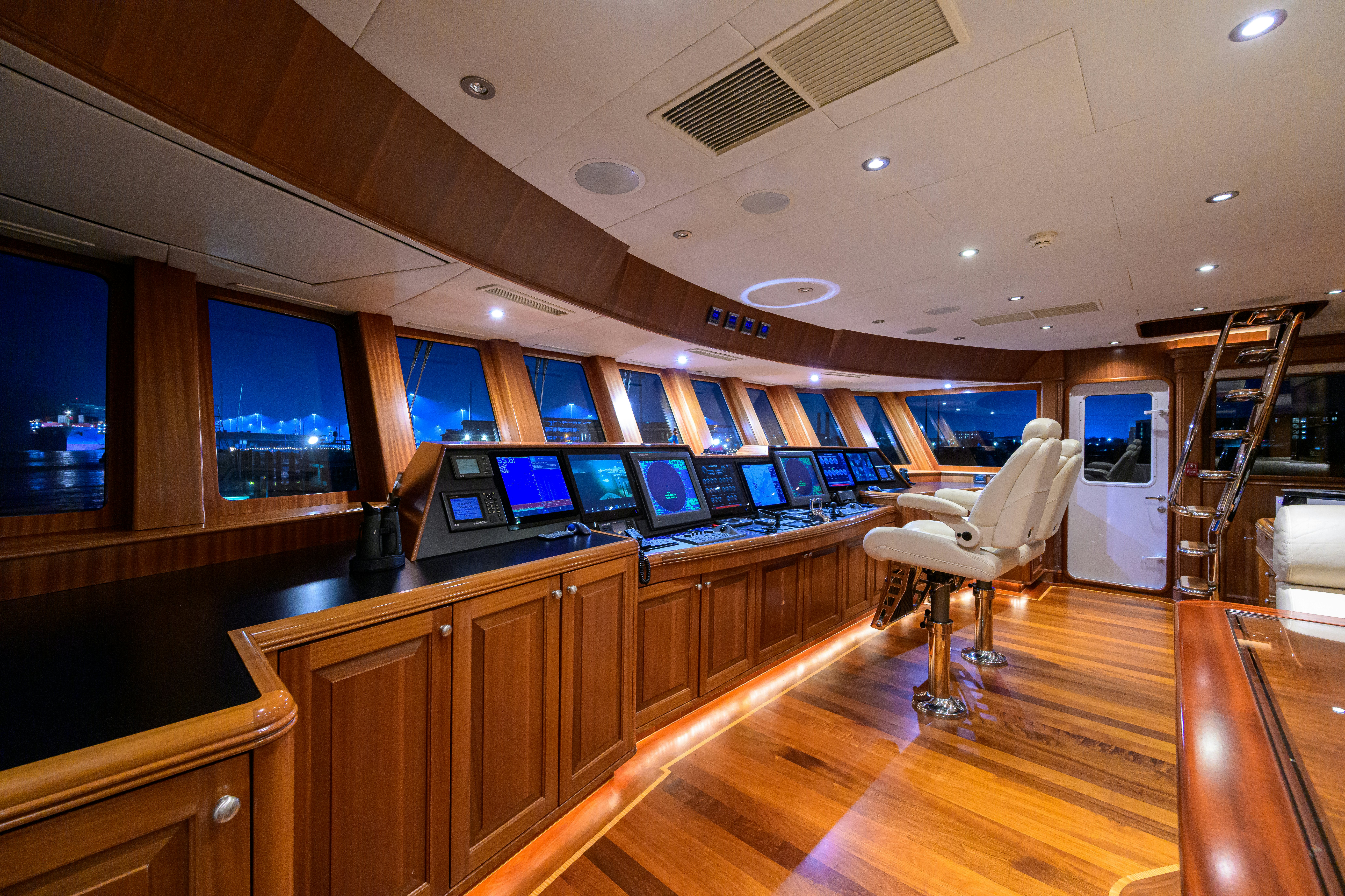 a room with a wood floor and a desk with computers and a large window with a wood floor aboard COMPASS ROSE Yacht for Sale