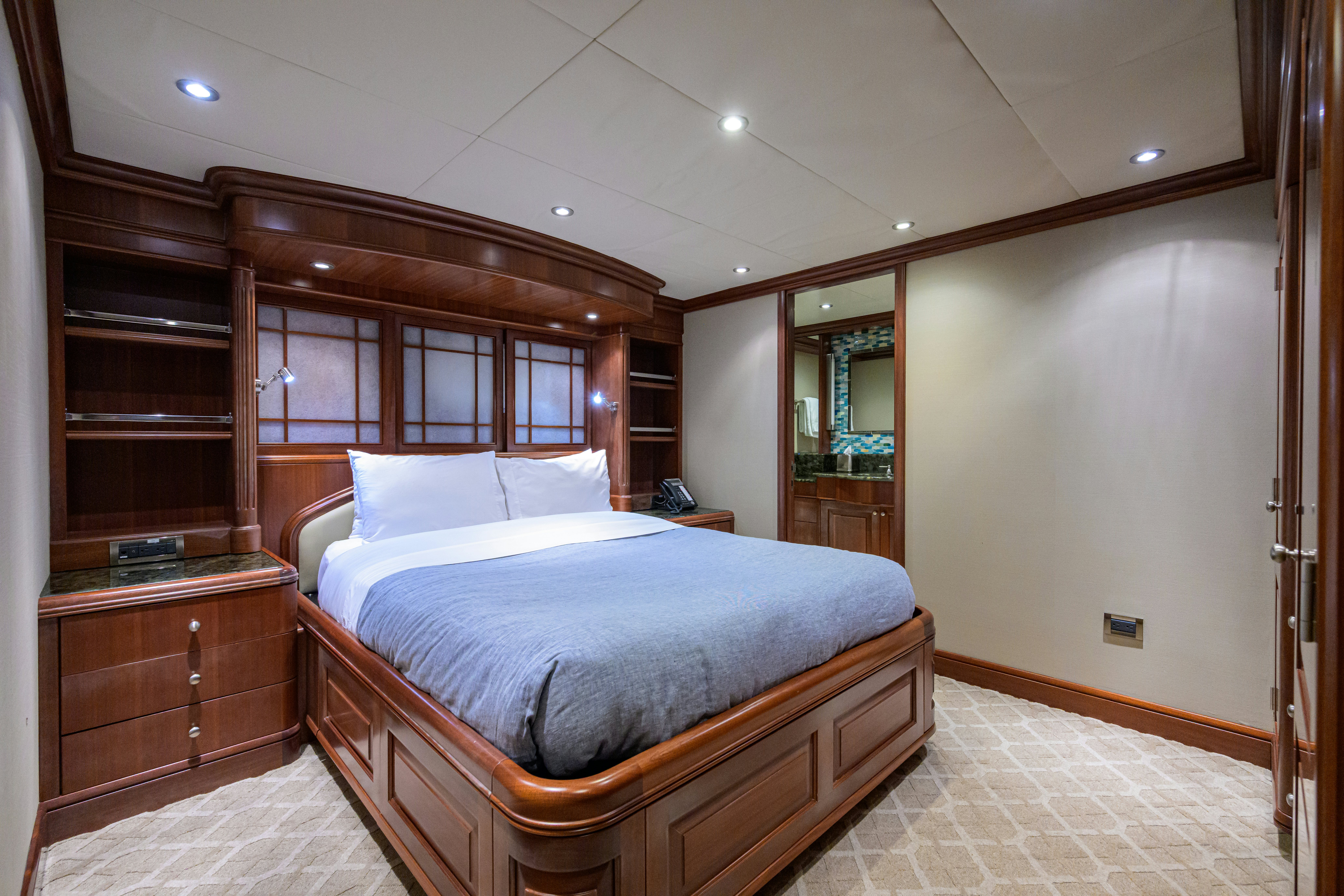 a bedroom with a bed and a desk aboard COMPASS ROSE Yacht for Sale