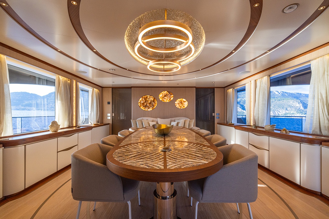 a large living room with a round table and a large chandelier aboard ANJELIF Yacht for Charter