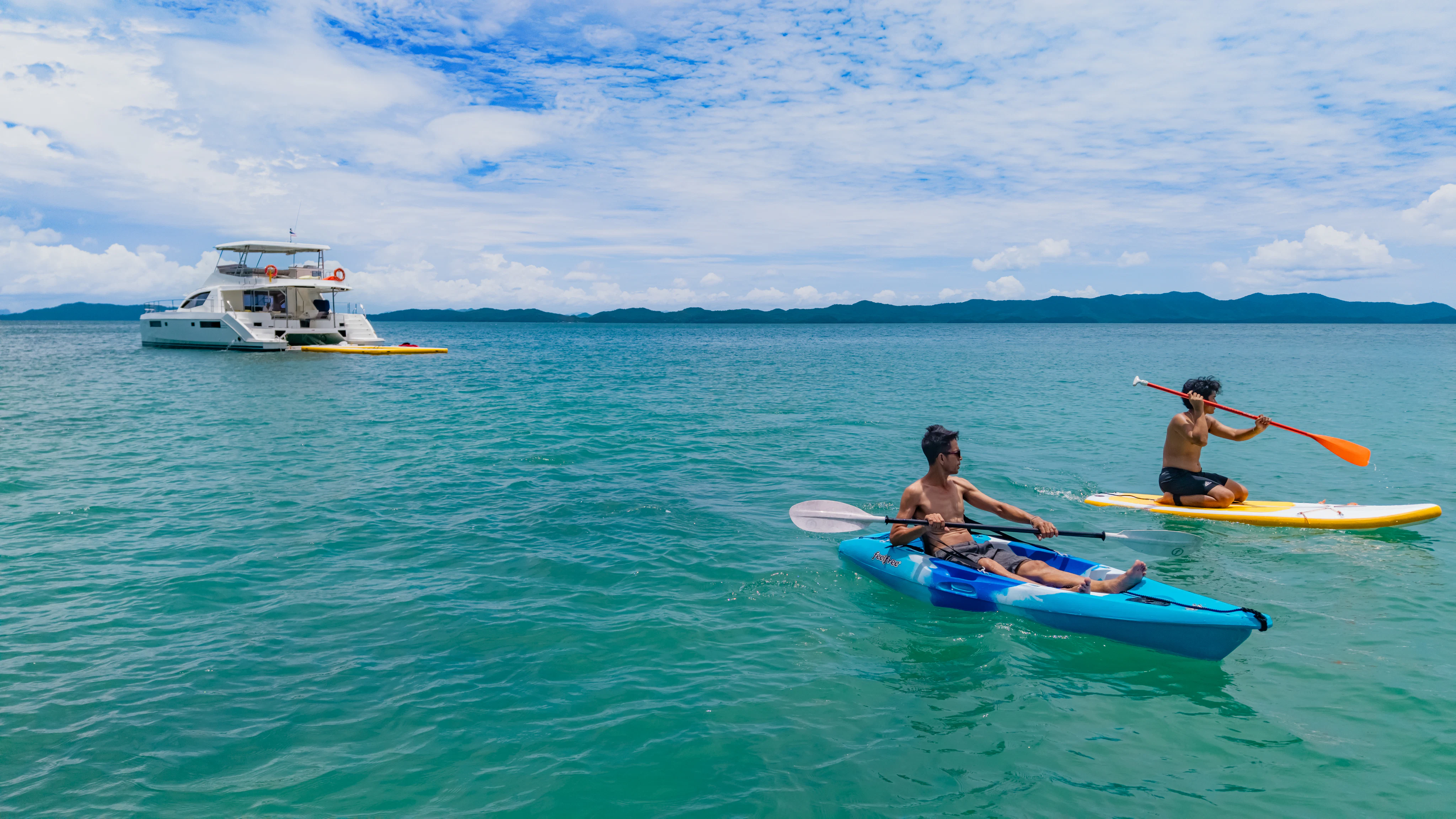 two people in kayaks in the ocean with a boat in the background aboard HARMONY CAT Yacht for Sale