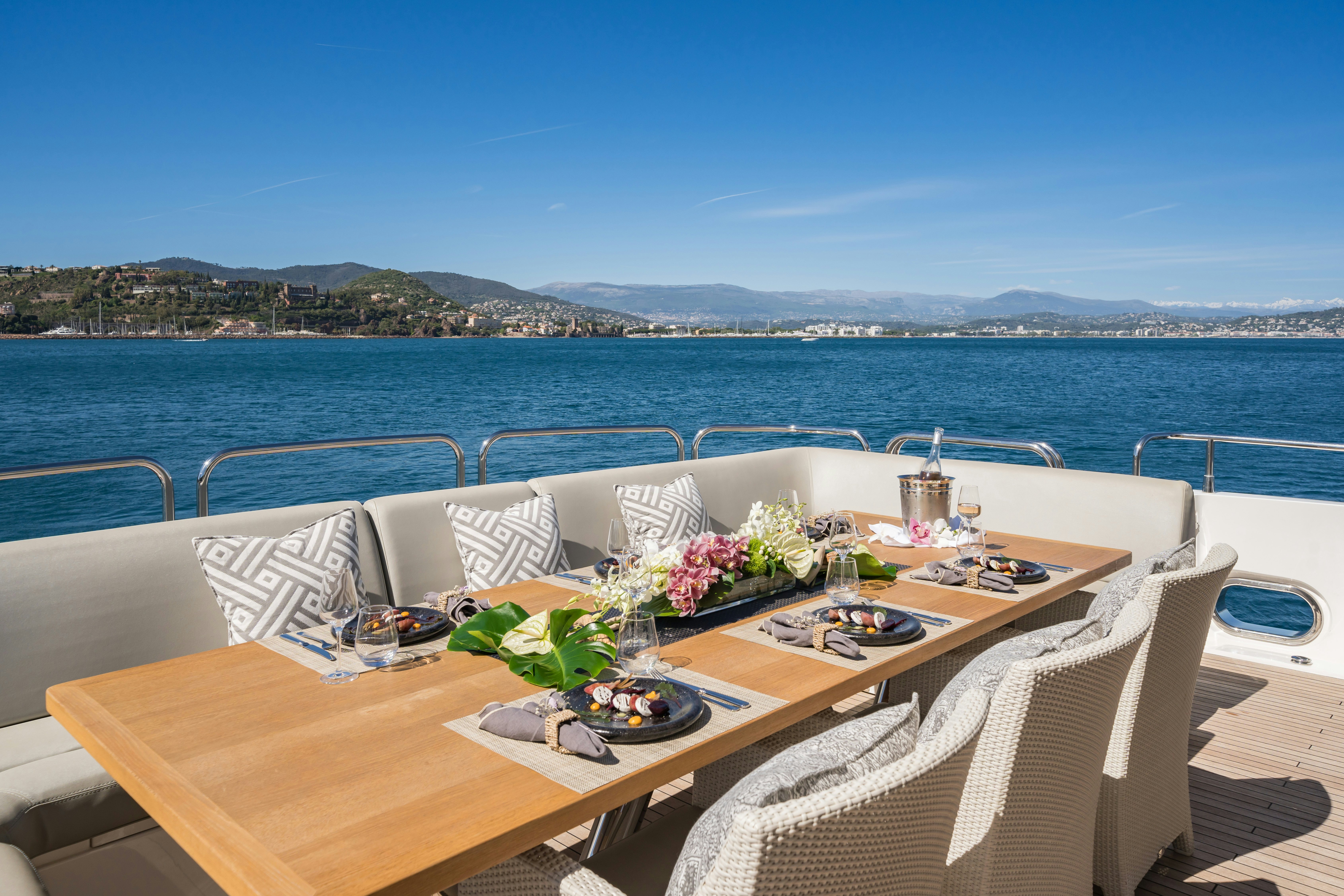 a table with plates and flowers on it on a boat aboard LADY VOLANTIS Yacht for Sale
