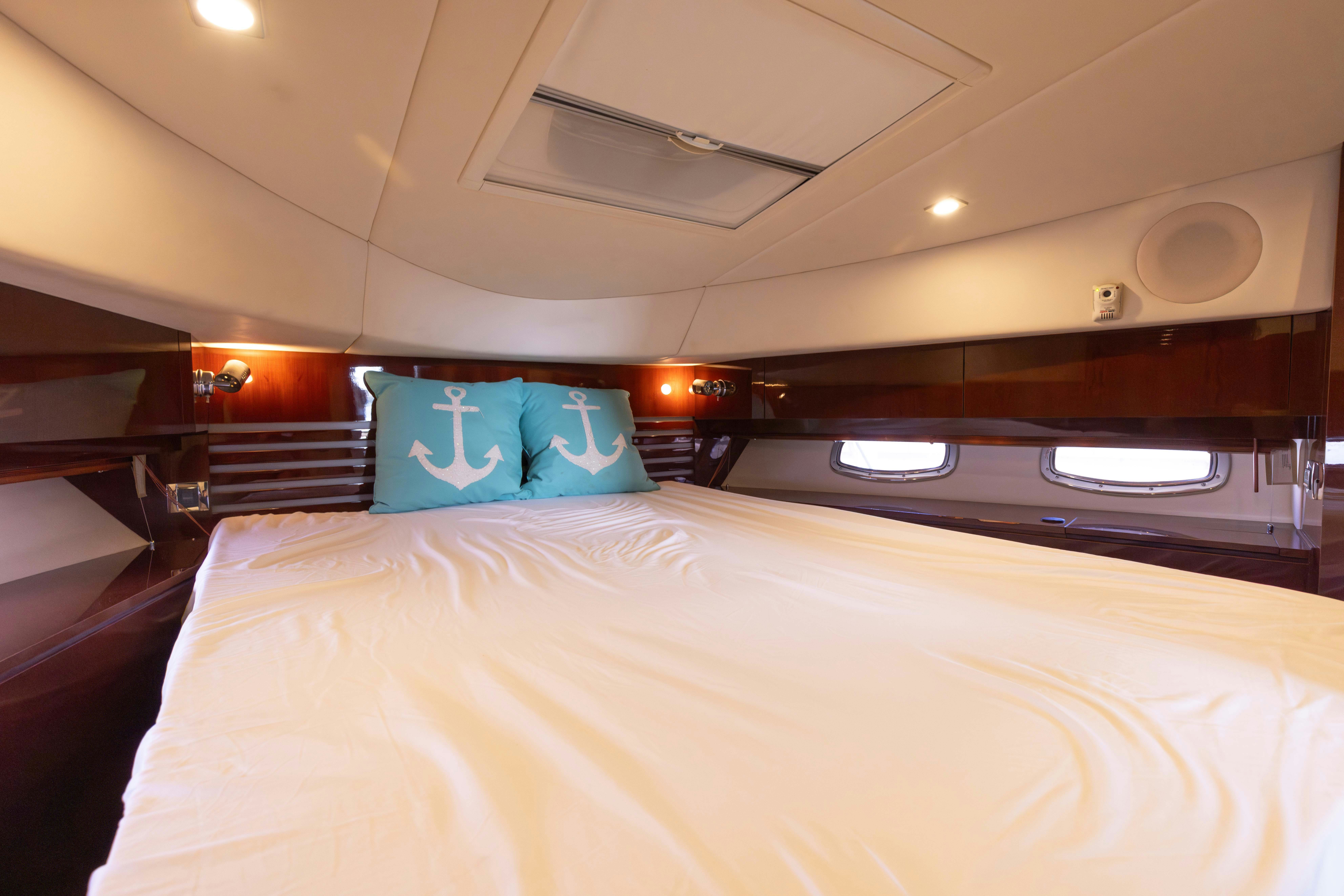 a bed with a white sheet and blue pillow aboard KA-BAR Yacht for Sale