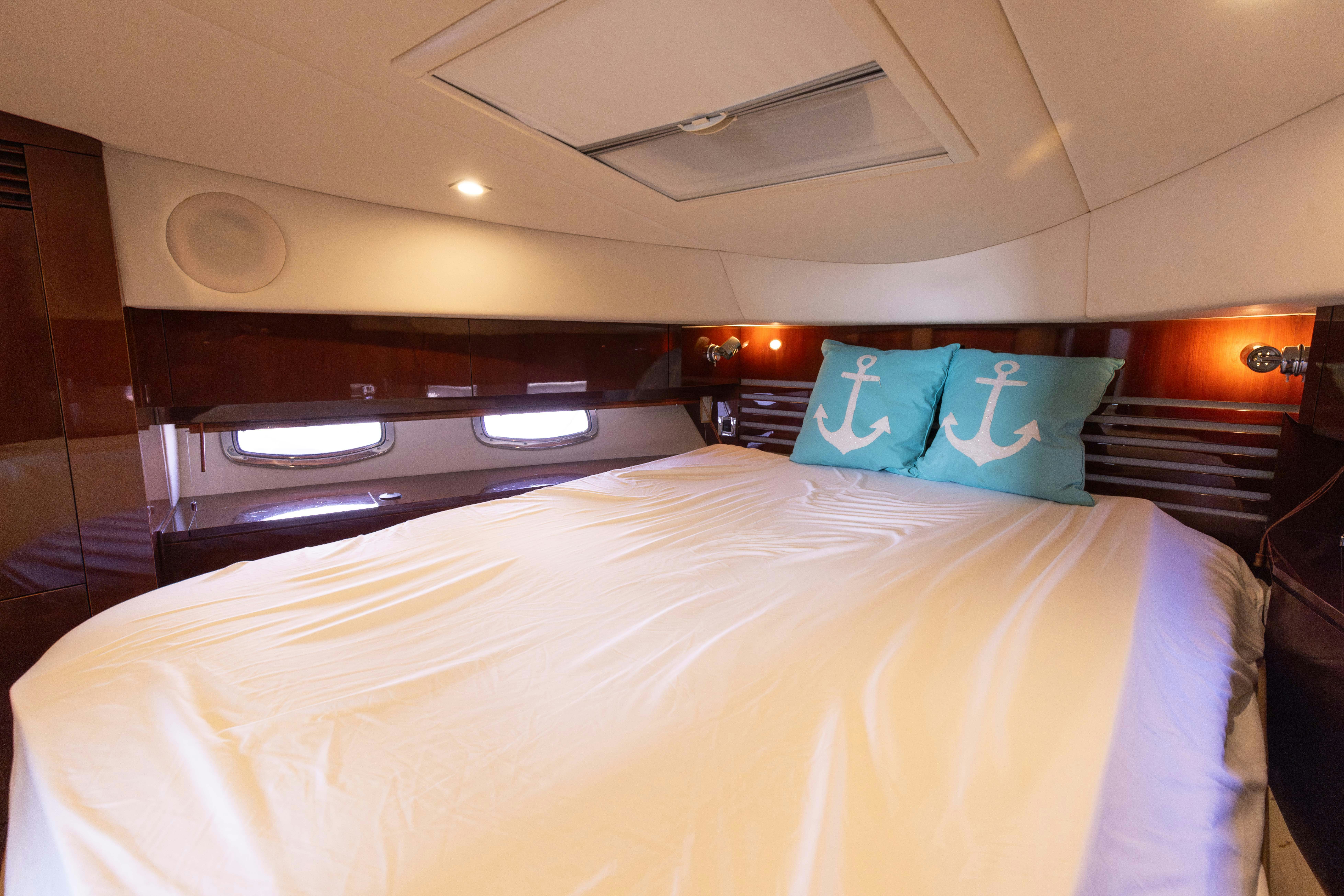 a bed with a white sheet and blue pillow aboard KA-BAR Yacht for Sale