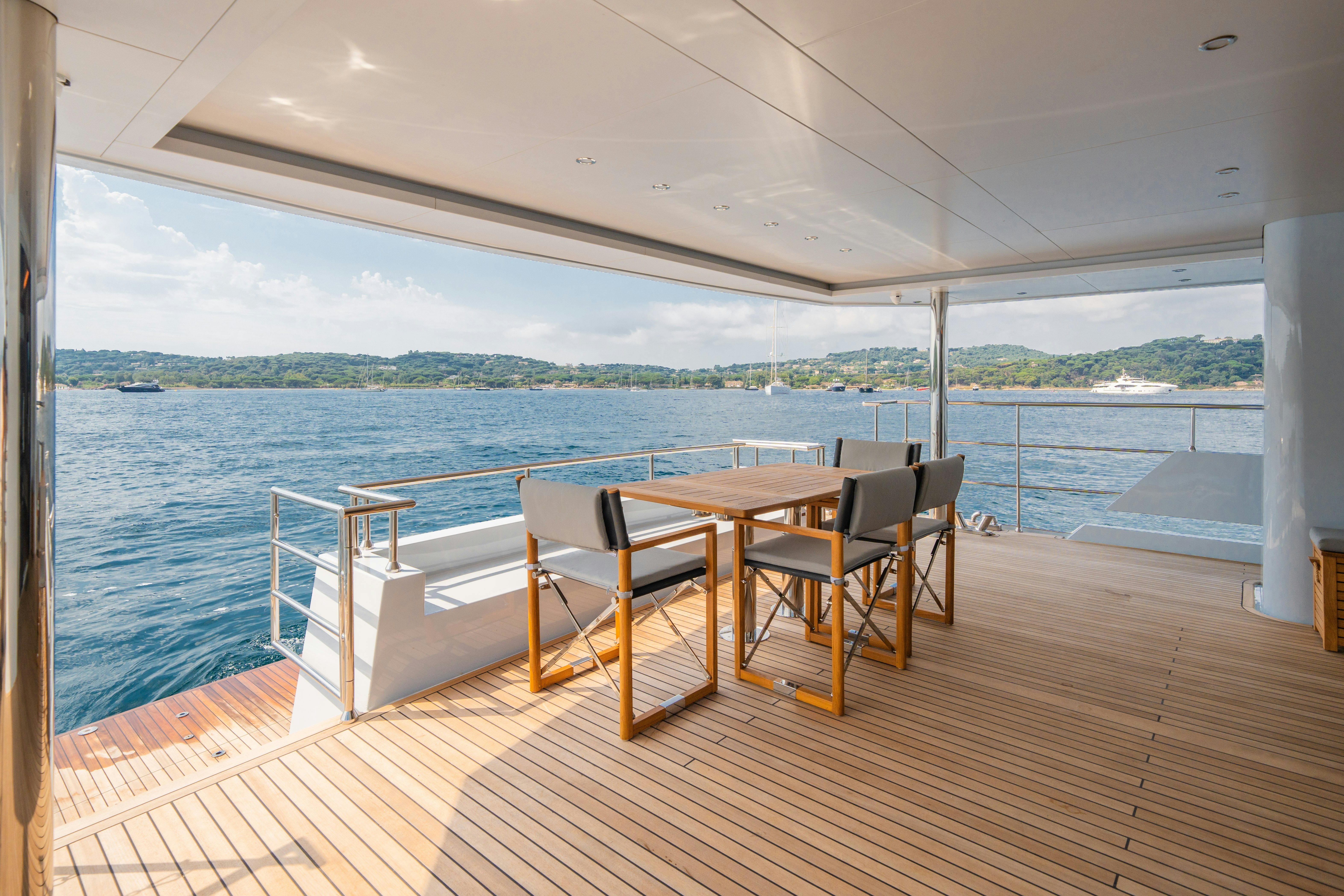a deck with a table and chairs on it aboard ICE Yacht for Sale