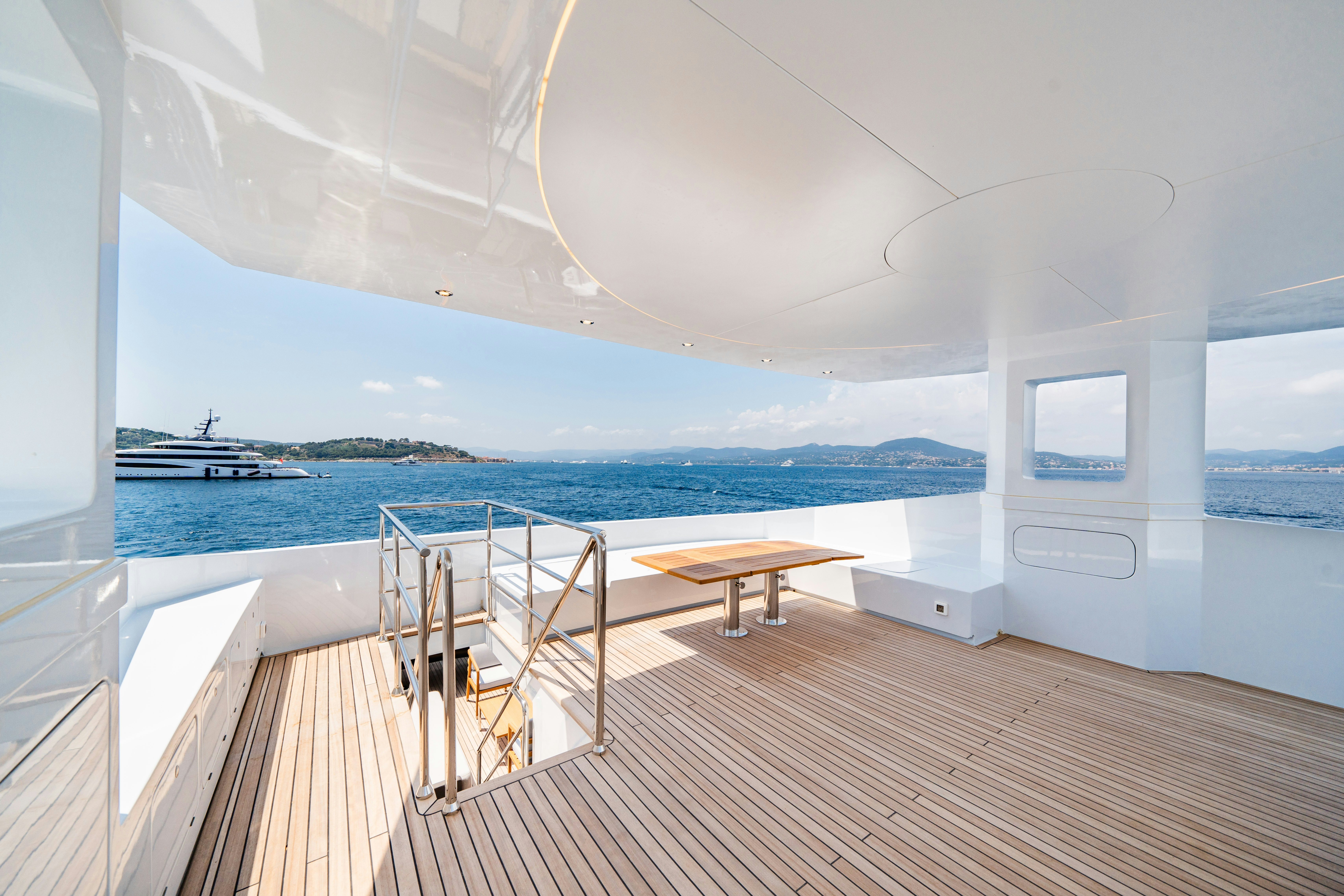 a room with a table and chairs on a deck by the water aboard ICE Yacht for Sale