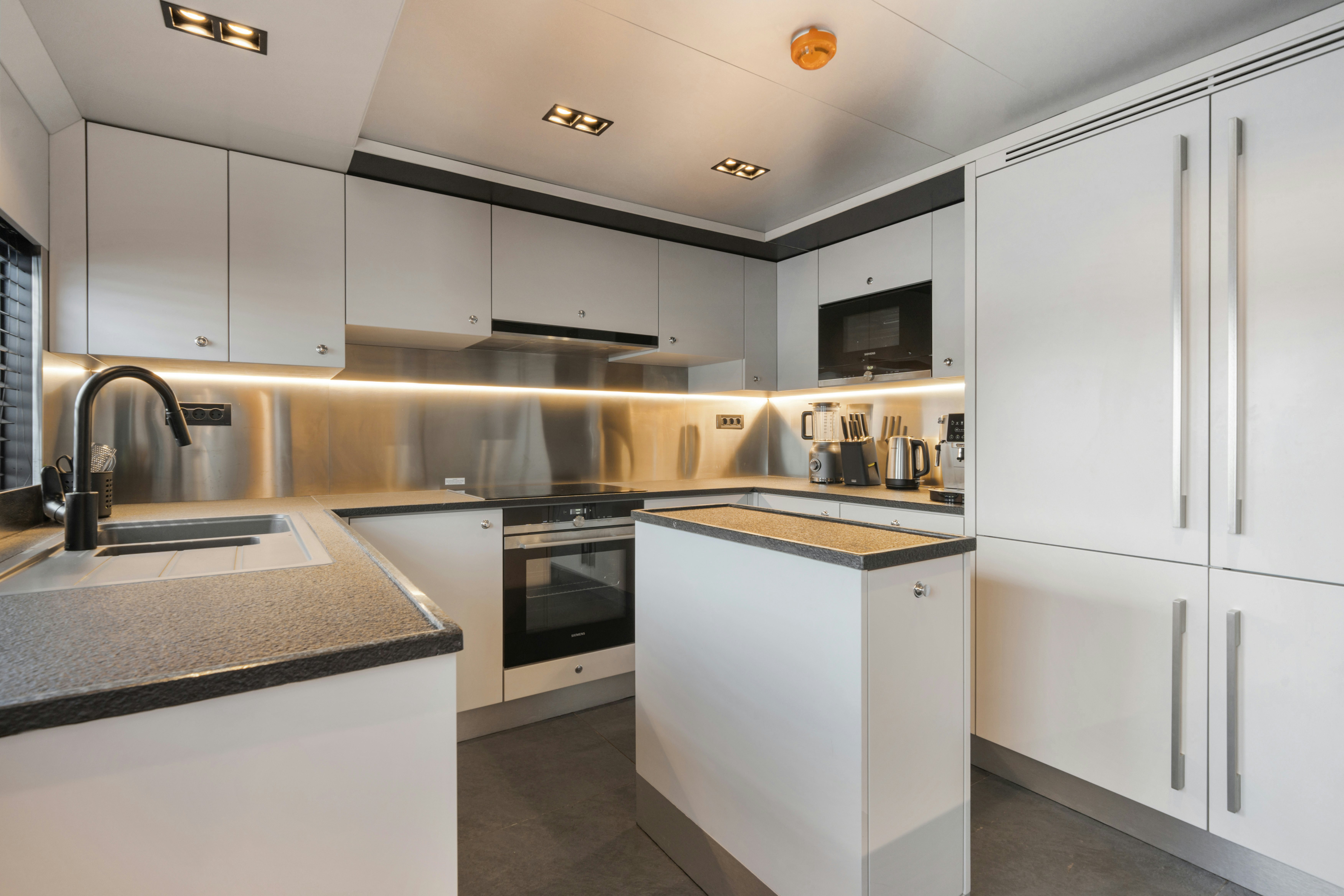a kitchen with white cabinets aboard ICE Yacht for Sale