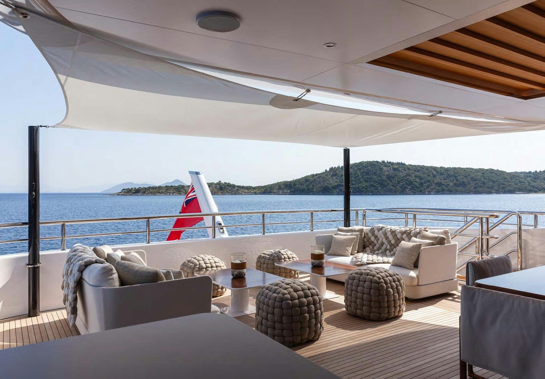 a large patio with a large body of water and a large boat in the background aboard ALUNYA Yacht for Charter