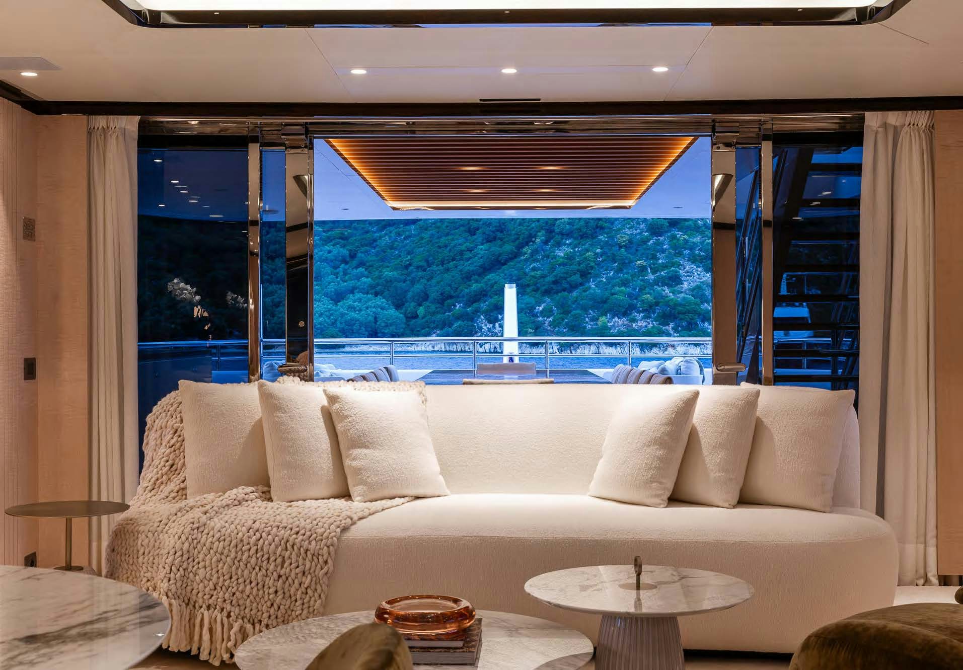 a large white couch with a large window overlooking a city aboard ALUNYA Yacht for Charter