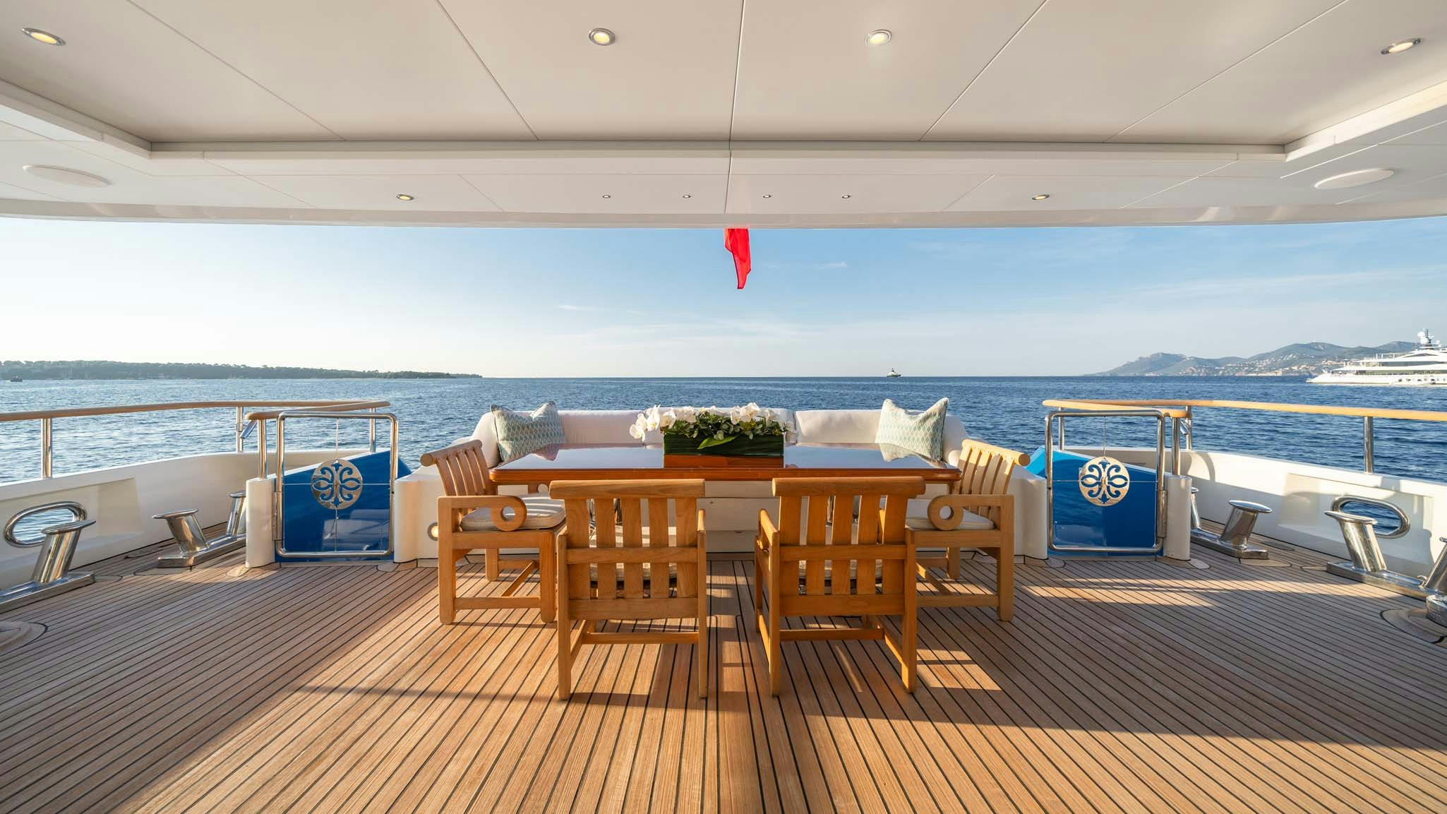 a deck with chairs and tables on it by the ocean aboard MOSAIQUE Yacht for Charter