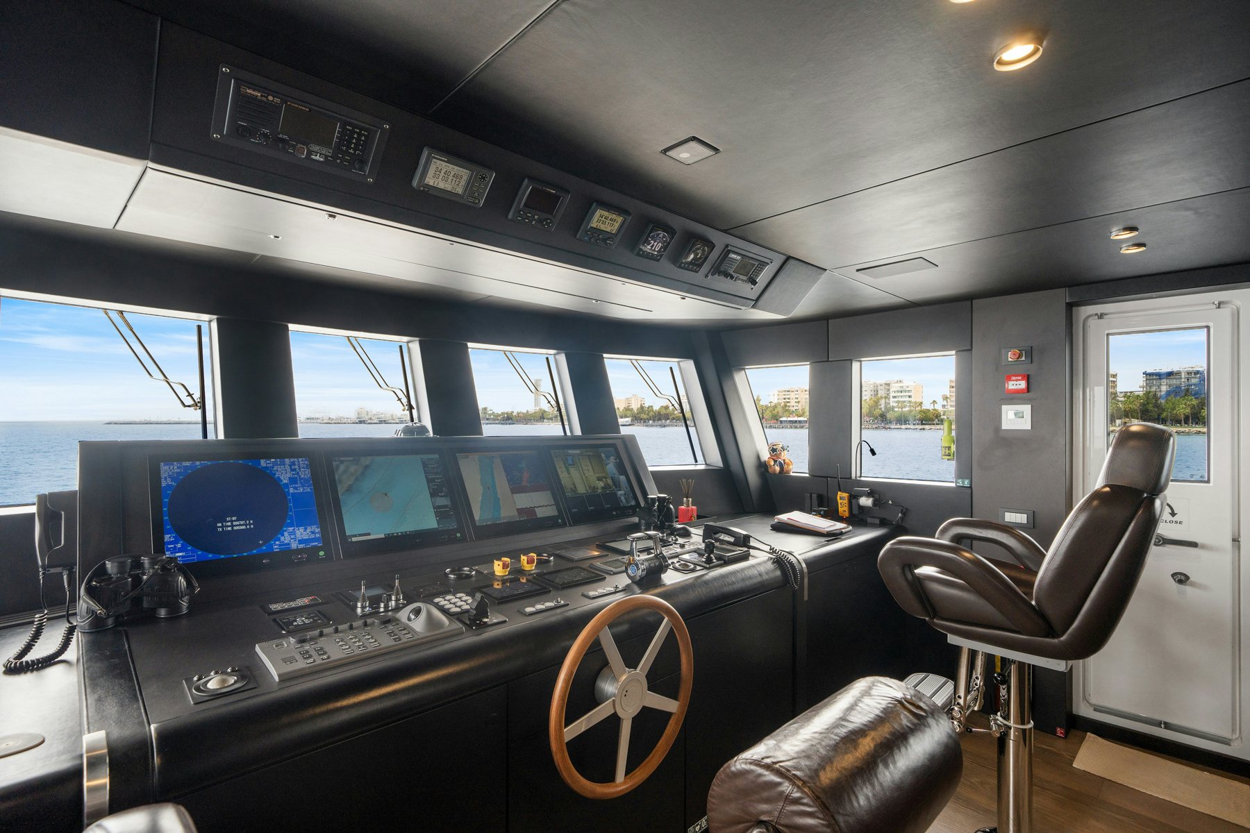 a music studio with a large black piano and a large screen with many screens and windows aboard CAPE COD II Yacht for Sale