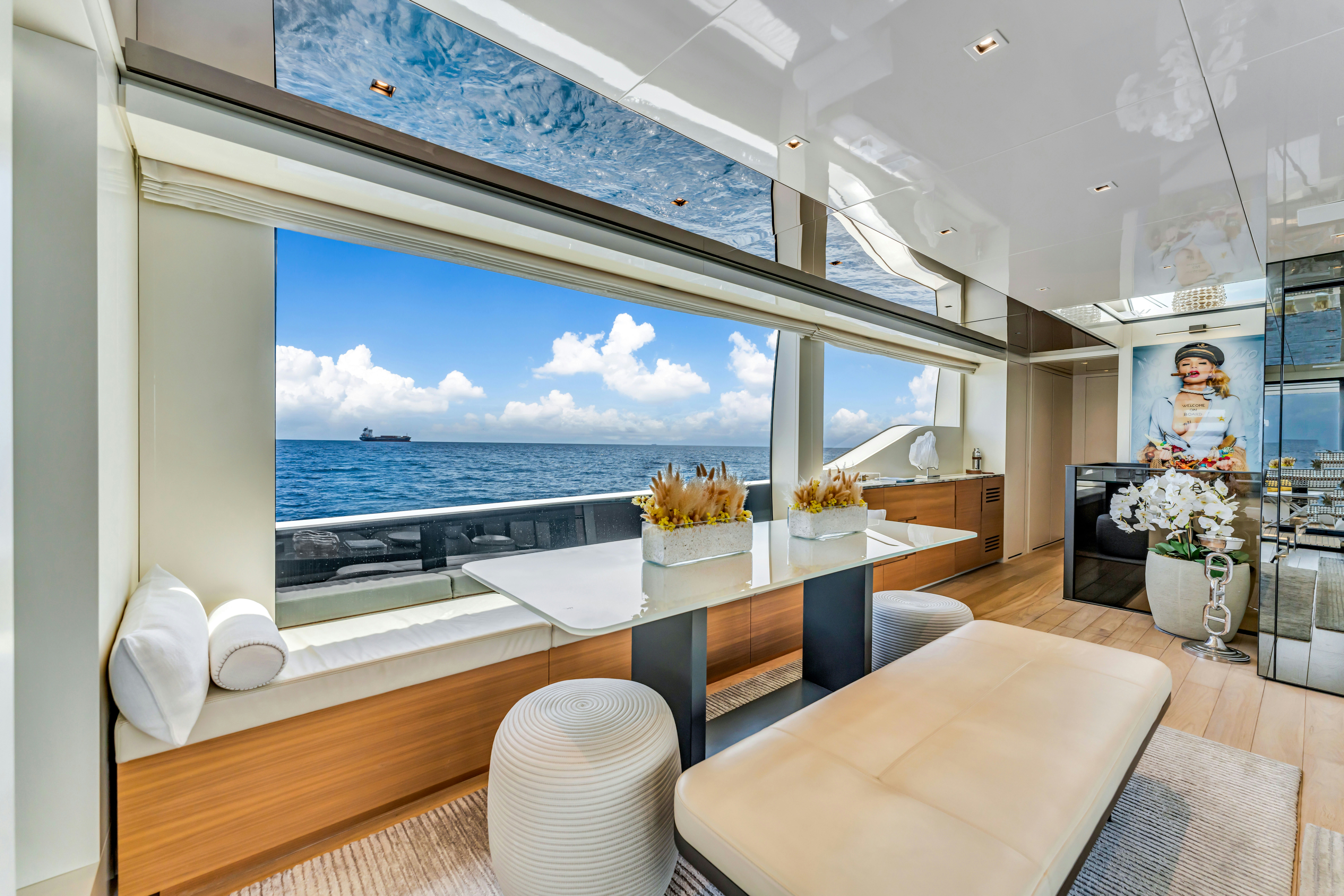 a room with a large window and a table with chairs and flowers aboard NOTYNOG Yacht for Charter
