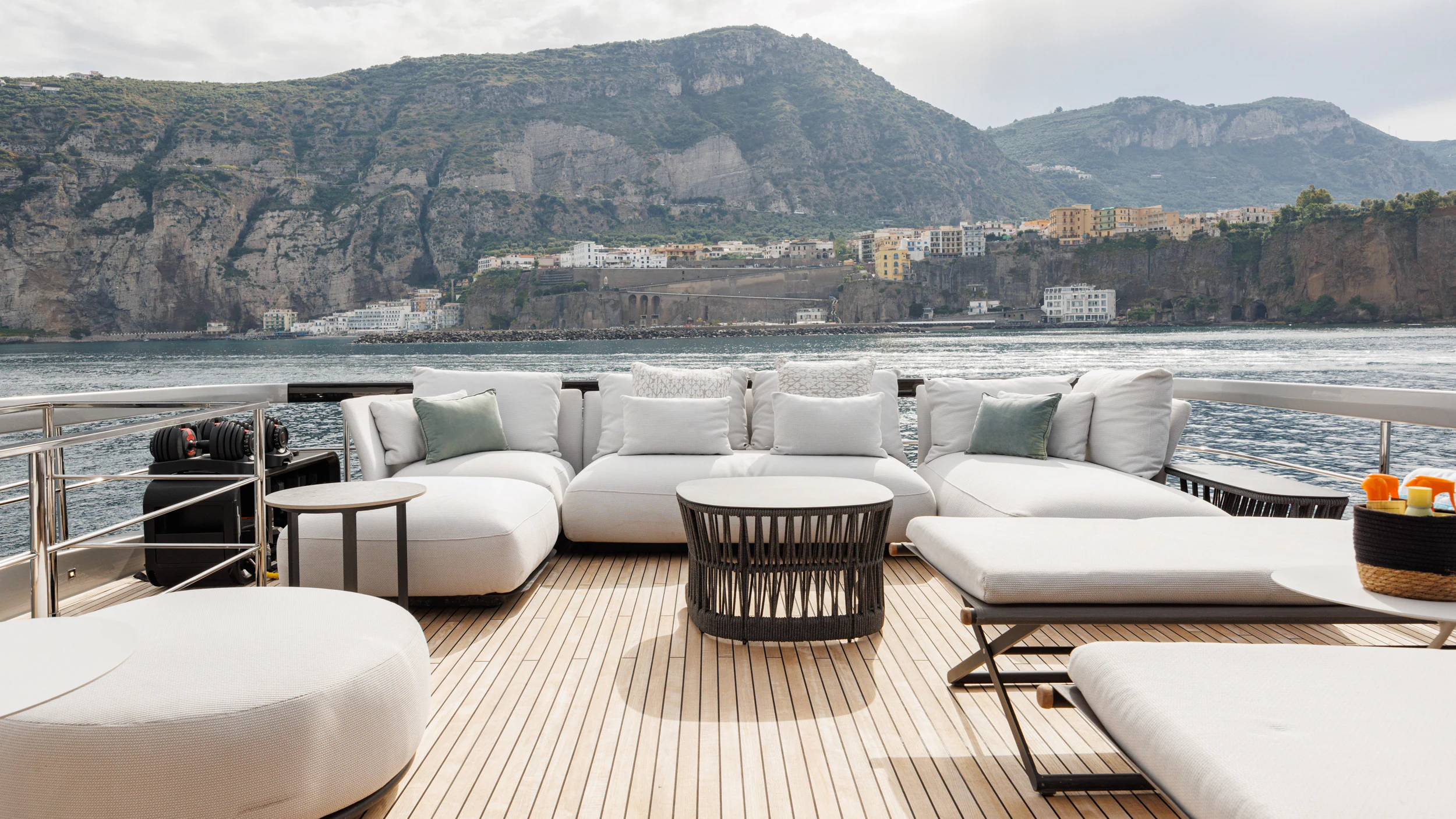 a room with a couch and a table and chairs on a deck with a view of a city aboard STILE DI VITA Yacht for Charter