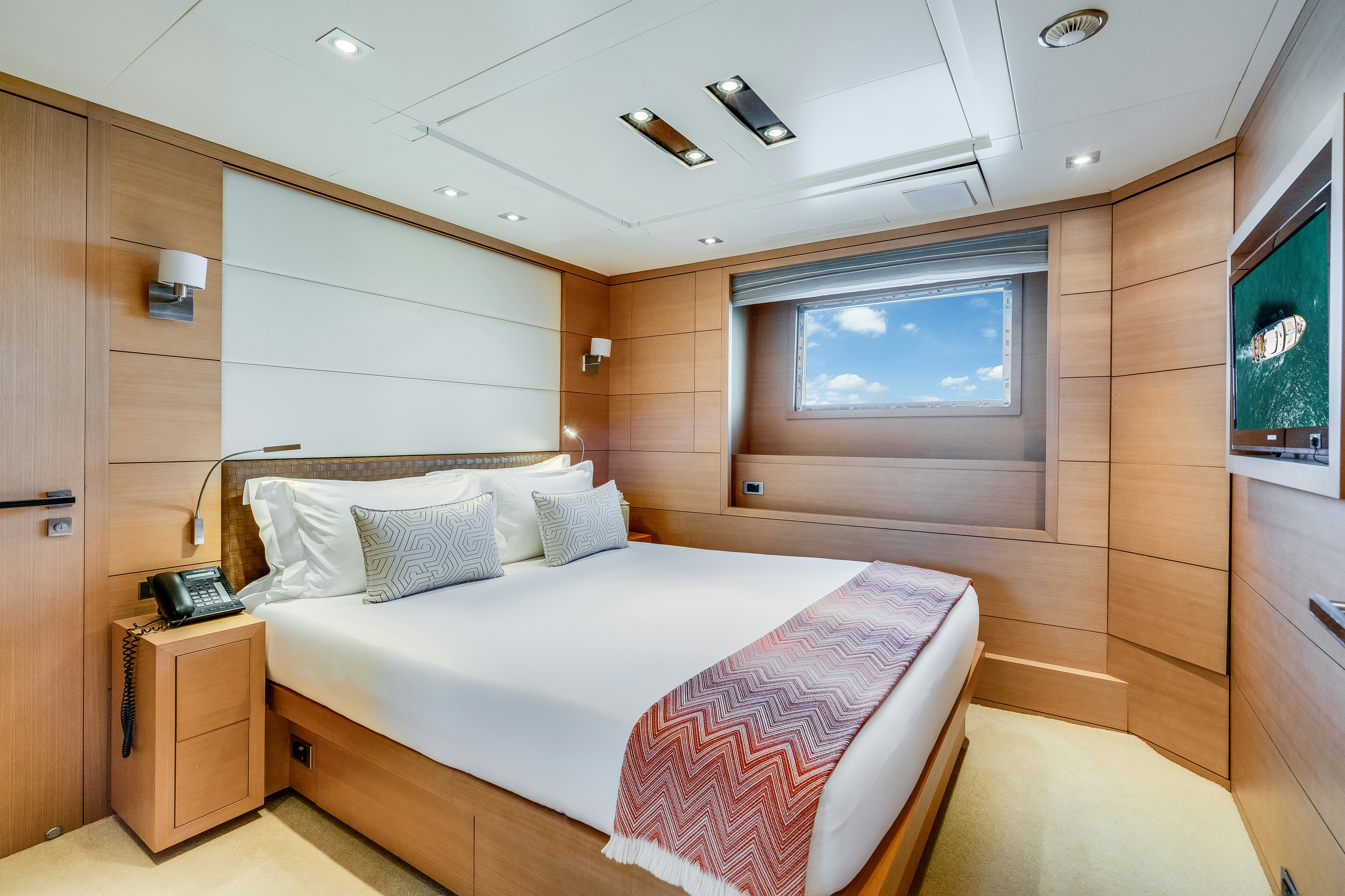 a bedroom with a bed and a wood cabinet aboard LADY H Yacht for Charter