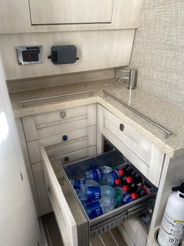 a kitchen counter with a sink and a shelf with bottles aboard RELAPSE Yacht for Sale
