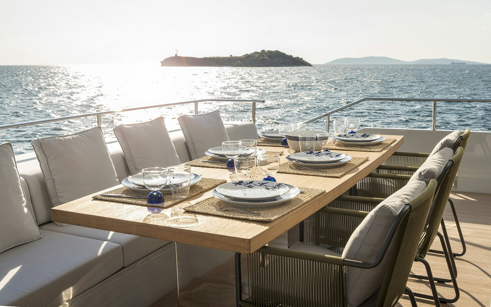 a table with plates and chairs on it by the ocean aboard IGUAZU Yacht for Sale