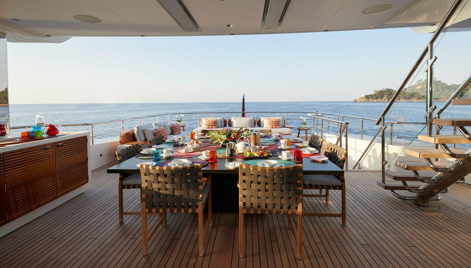 a table set for a meal on a deck overlooking the ocean aboard SOMNIUM Yacht for Sale